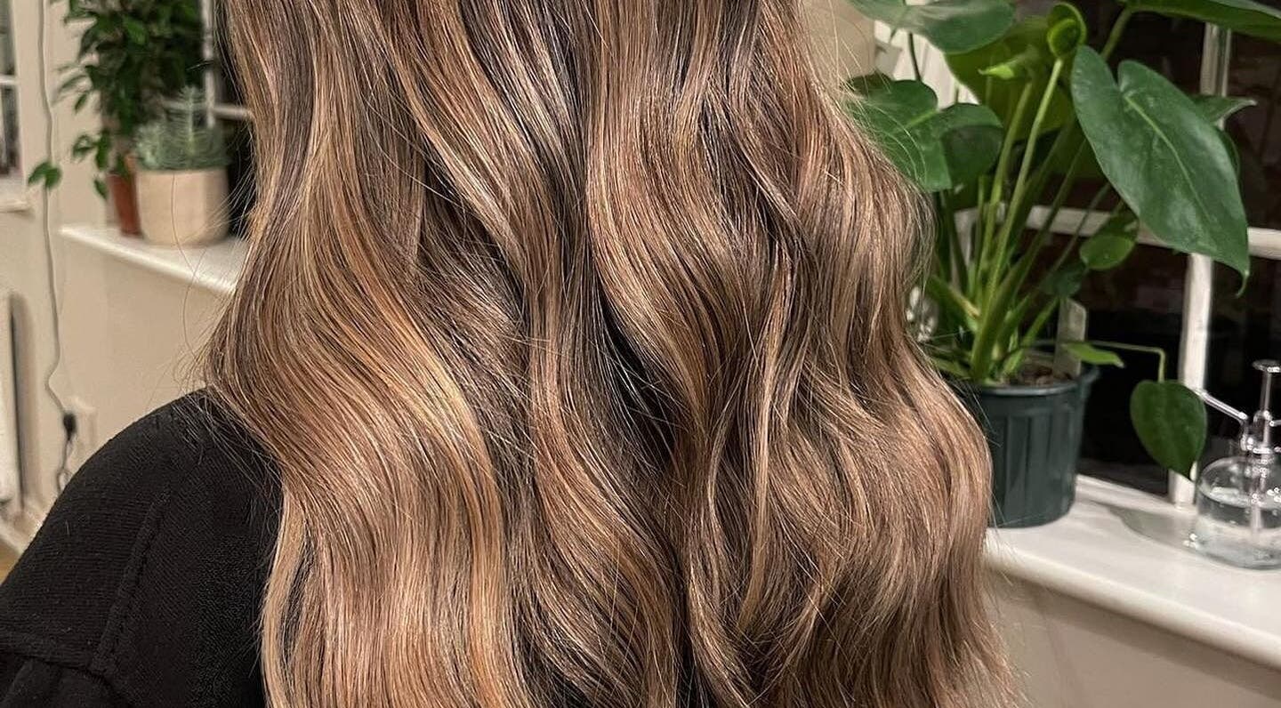 Beautifully styled wavy hair at The Green House Salon, Birmingham, England, GB with indoor plants.