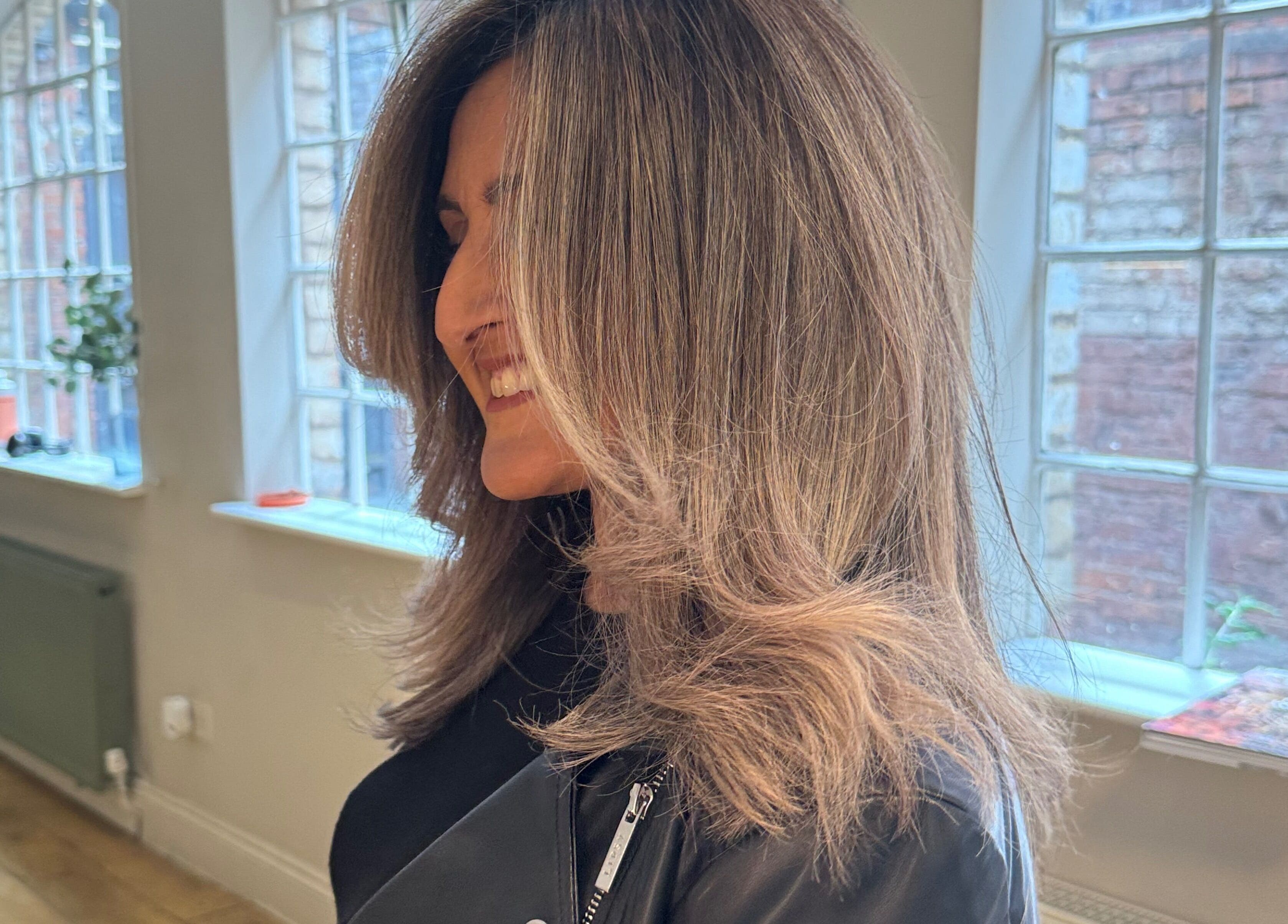Woman smiling with styled hair in The Green House Salon, Birmingham, England, GB.