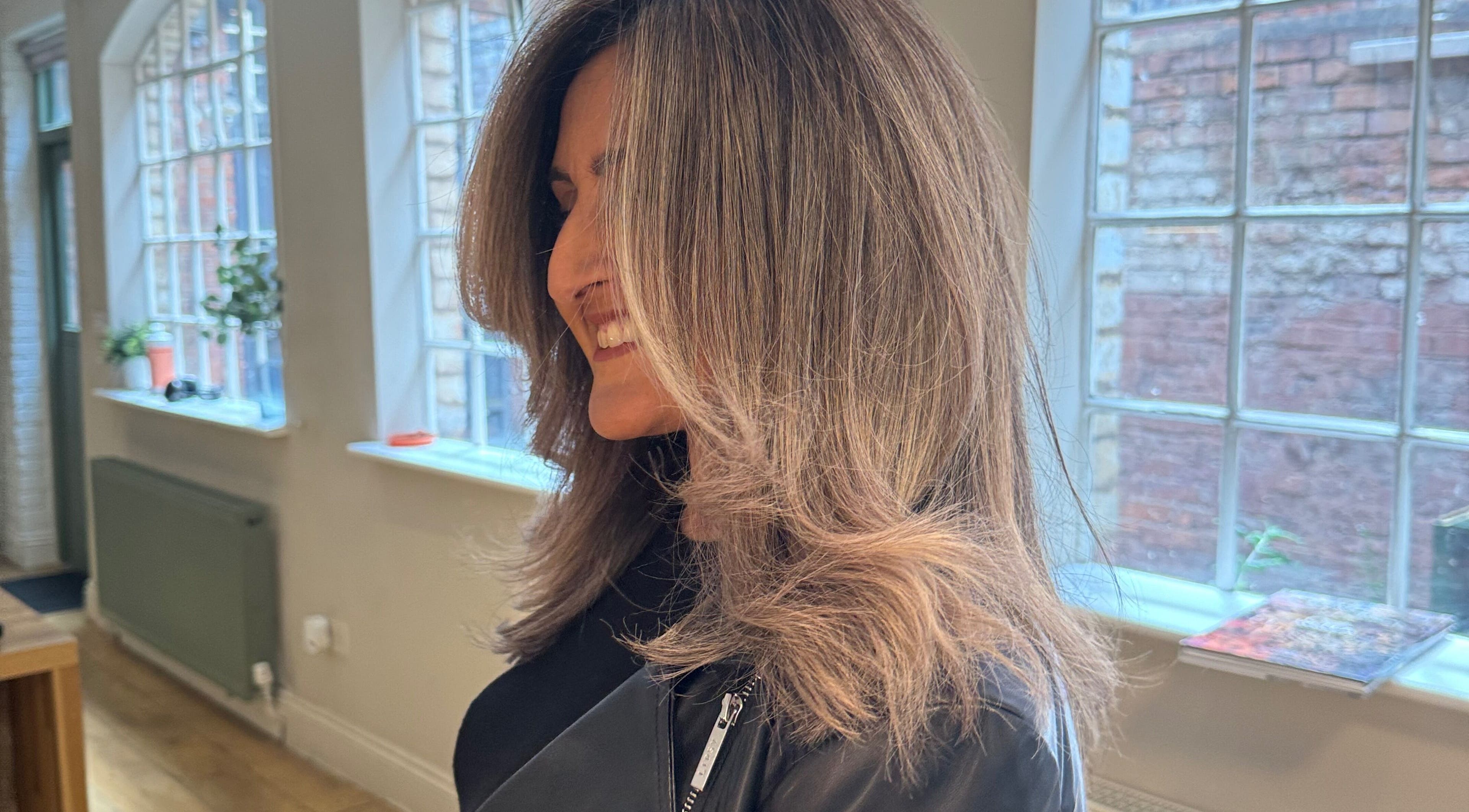 Woman smiling with styled hair in The Green House Salon, Birmingham, England, GB.