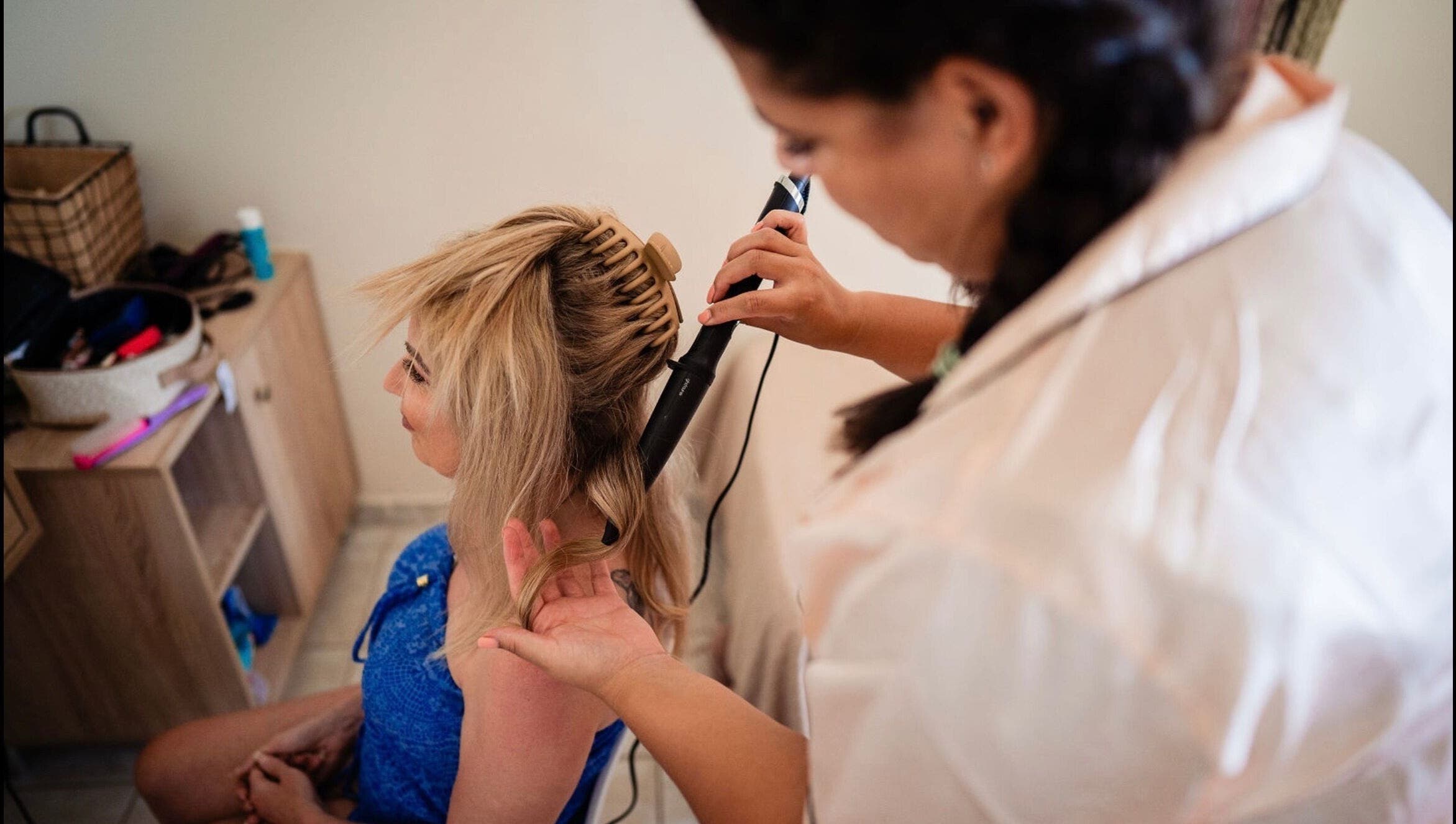 Woman getting hair styled with a curling iron at By Keeley, Leicester, England, GB.