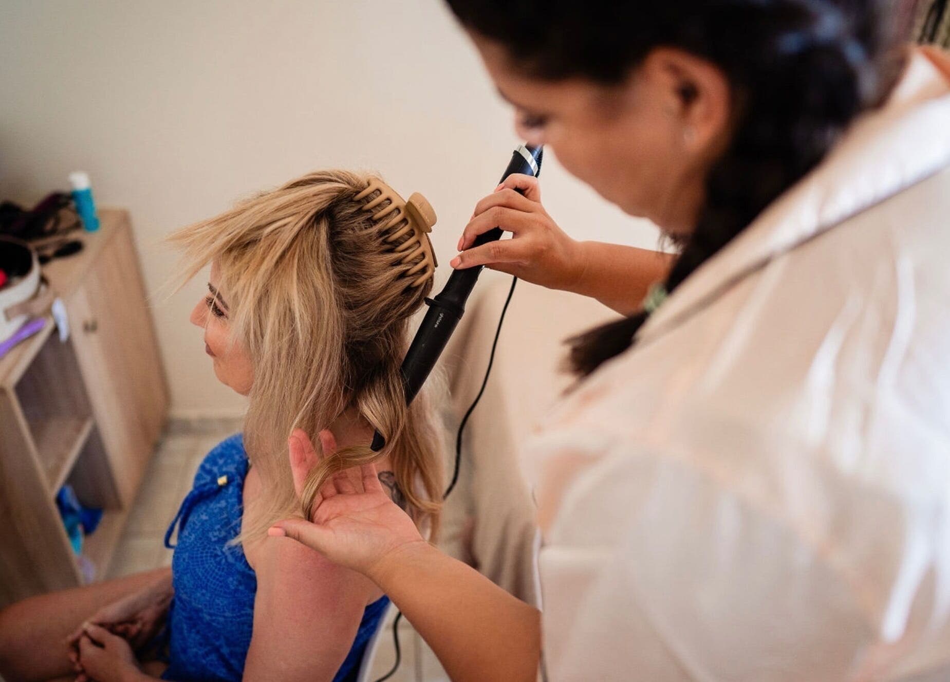 Woman getting hair styled with a curling iron at By Keeley, Leicester, England, GB.