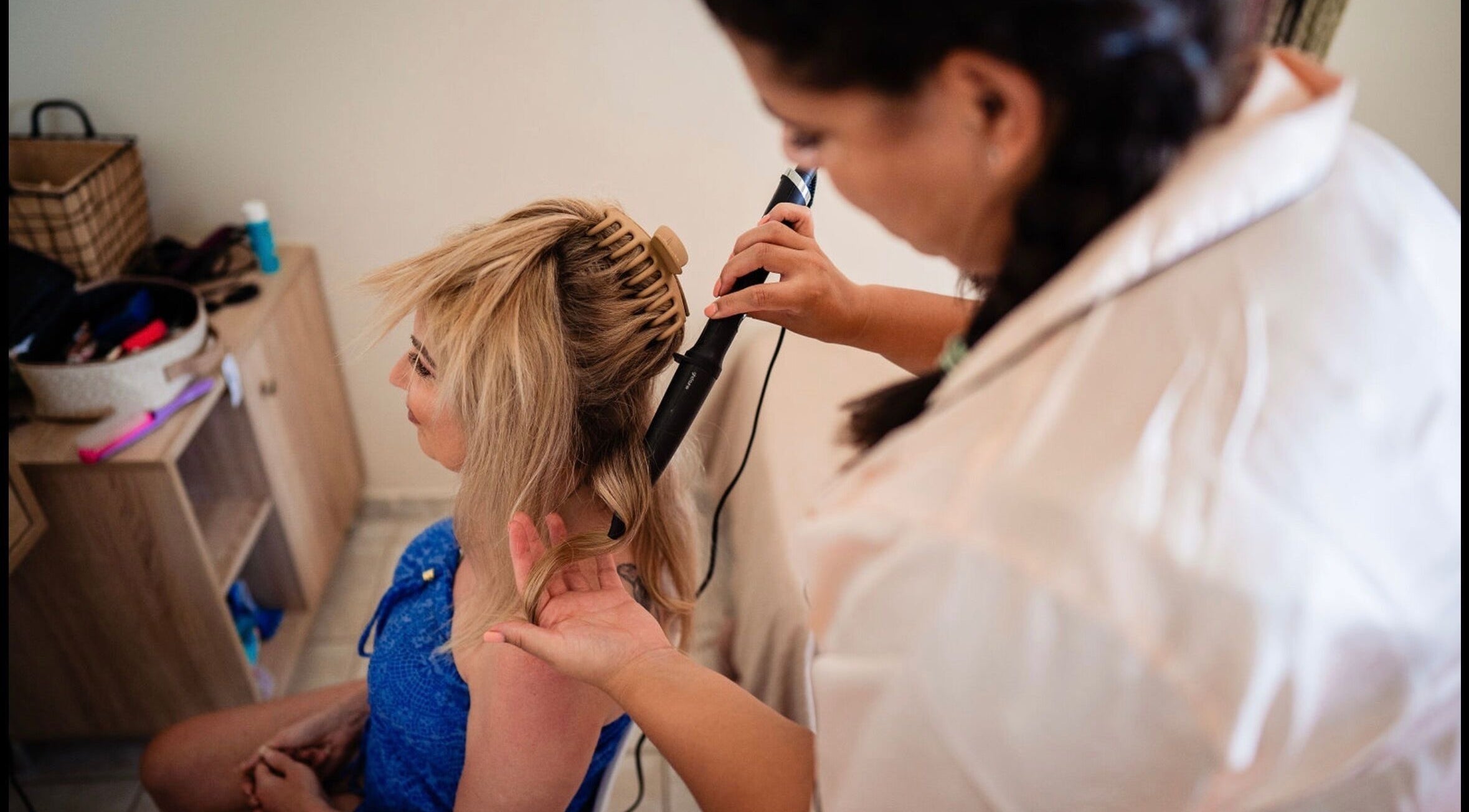 Woman getting hair styled with a curling iron at By Keeley, Leicester, England, GB.