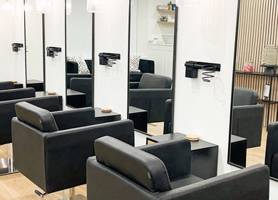 Elegant interior of The Hair Edit in Manchester, England with sleek black salon chairs and large mirrors.