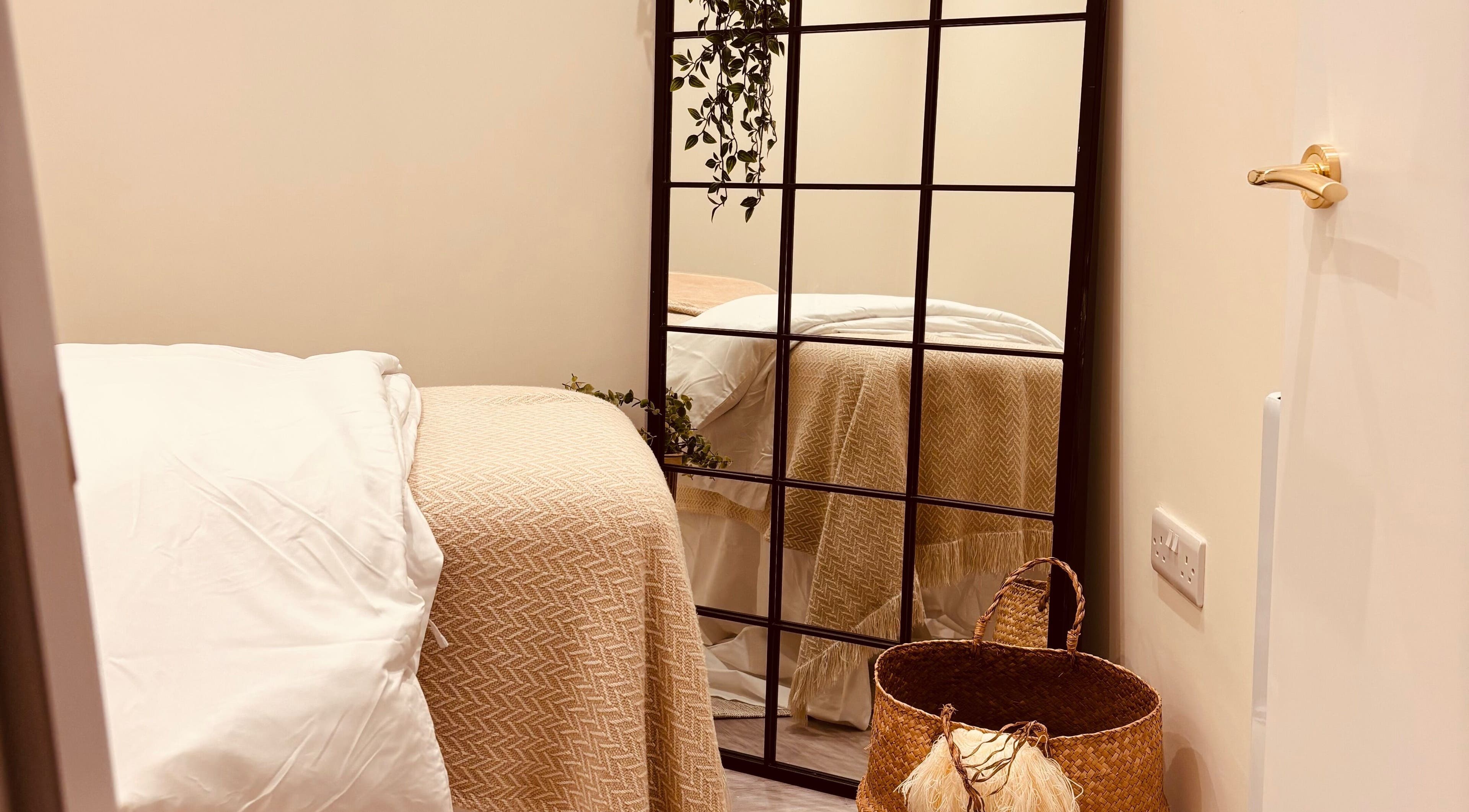 Tranquil treatment room at Peachy in Sherborne, England, GB, featuring a soft bed and decorative mirror.