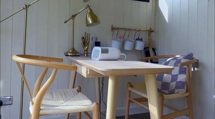 A cozy workspace at Sulking Room Studio, Horsham, England, GB, featuring wooden chairs and a table with decor.