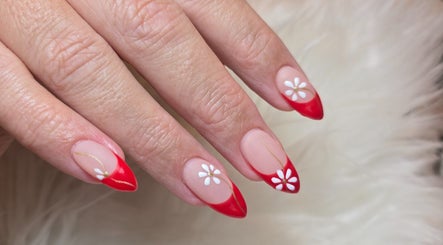Red-tipped nails with white daisy art at Scl Beauty, Southend-on-Sea, England, GB.