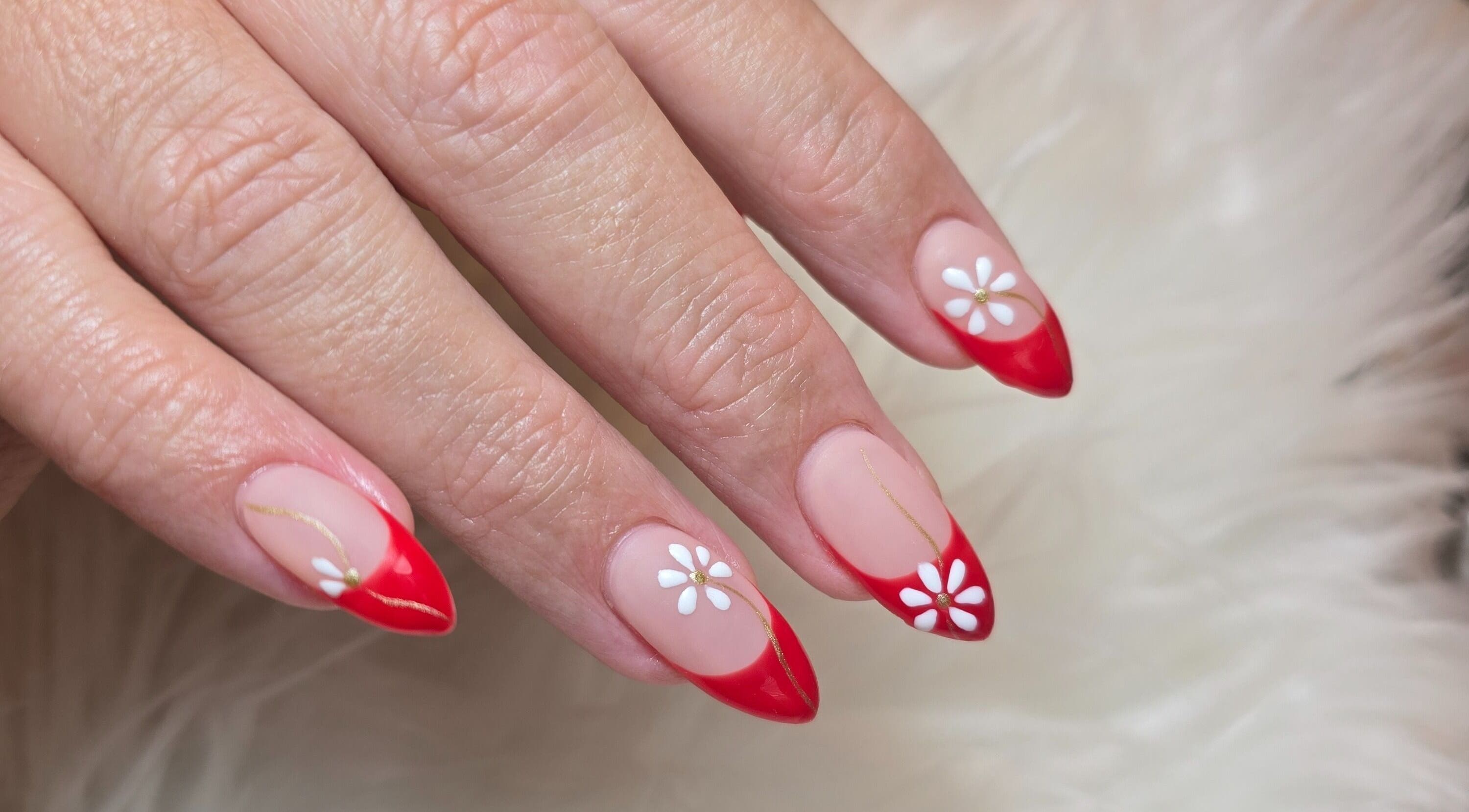 Red-tipped nails with white daisy art at Scl Beauty, Southend-on-Sea, England, GB.