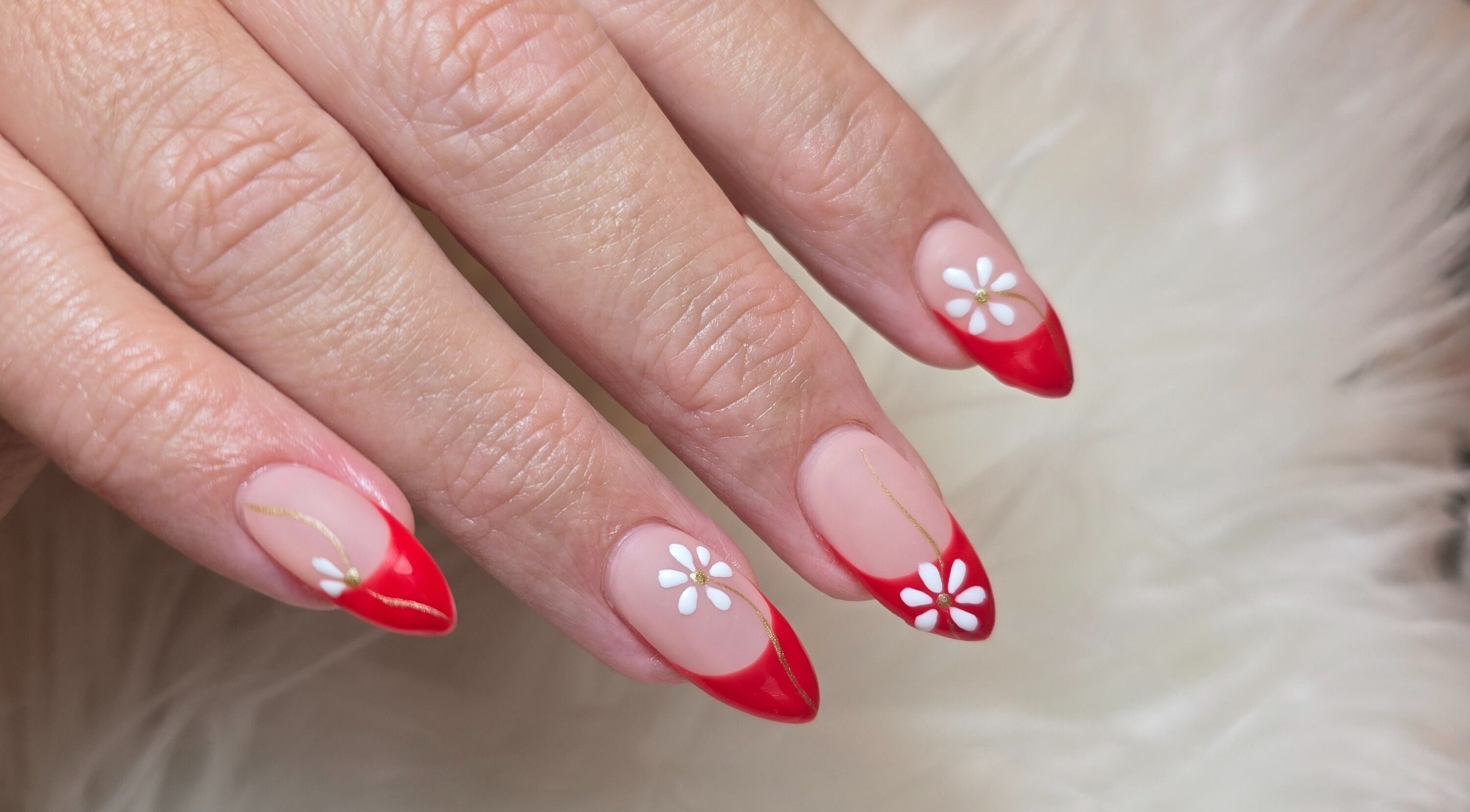 Red-tipped nails with white daisy art at Scl Beauty, Southend-on-Sea, England, GB.