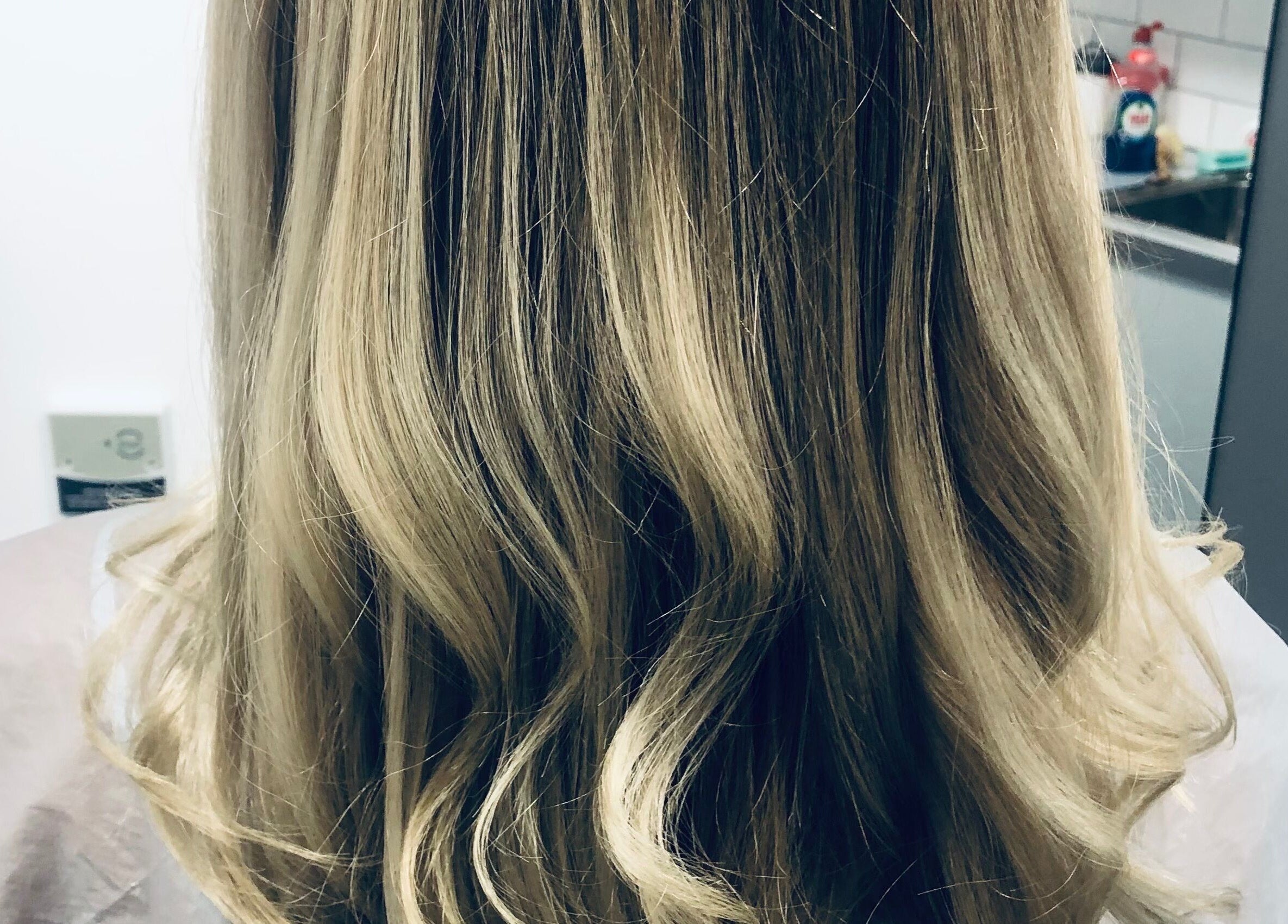 Blonde hair styled at Platinum HQ, Caerphilly, Wales, GB, showcasing smooth, elegant curls.