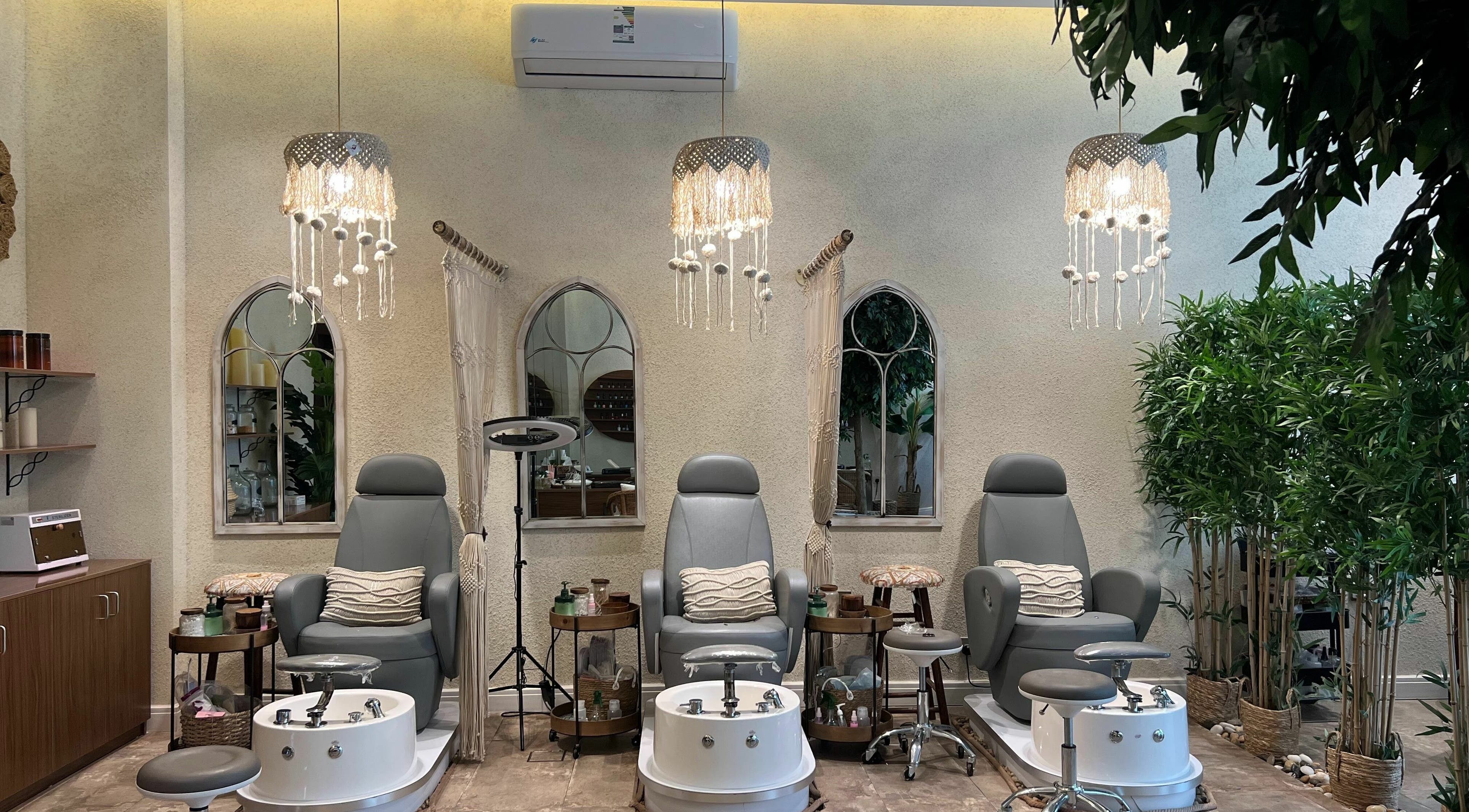 Cozy pedicure stations at Nails Oasis | واحة الاظافر, الرياض, منطقة الرياض, SA, under elegant chandeliers.