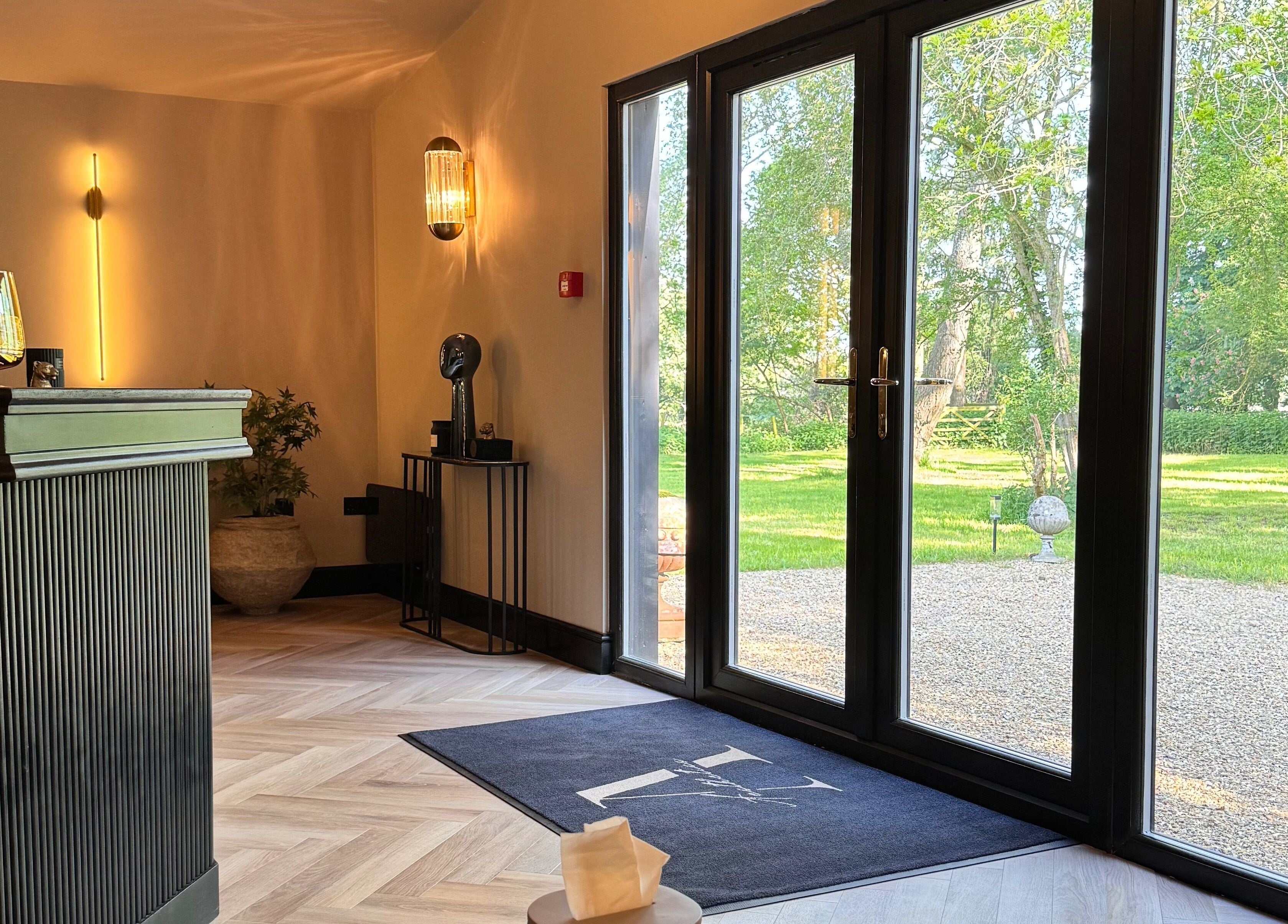 Bright entrance area at Antoinette Aesthetics, East Harling, England, with stylish decor and garden view.