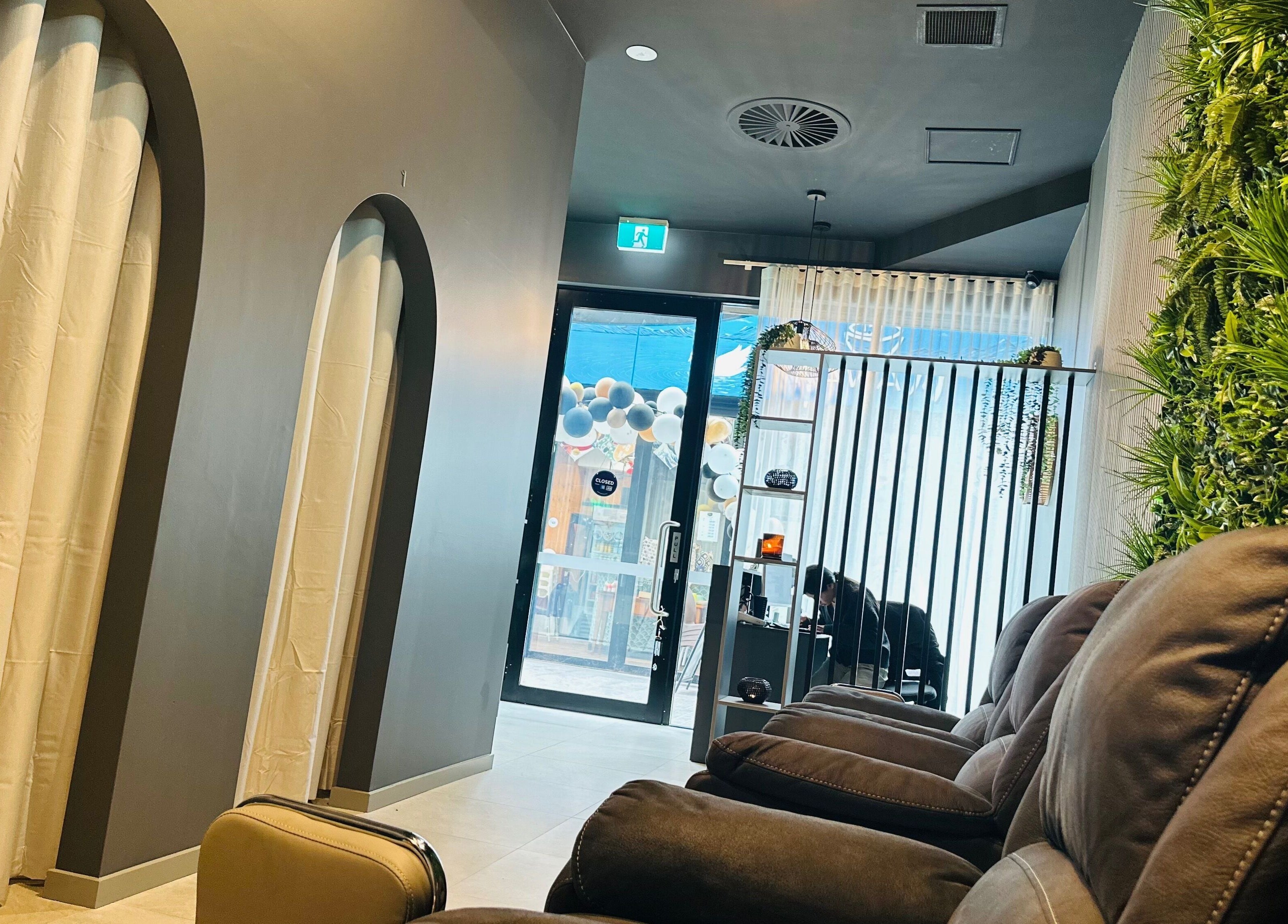 Relaxing lounge at Mel's Massage & Reflexology - Mount Lawley, featuring cozy seating and lush greenery.