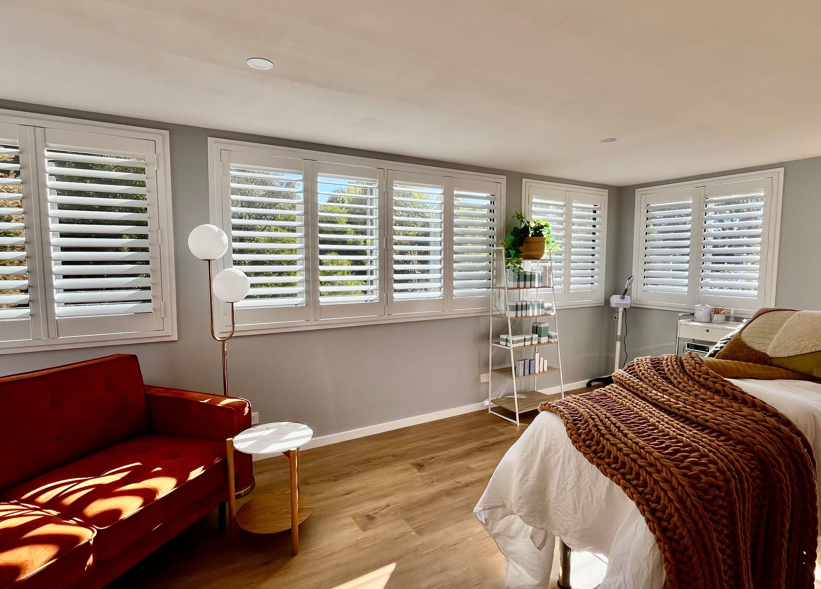 Bright treatment room at Skin Solace in Blackwood, Victoria, AU with cozy bed, red sofa, and light-filled windows.