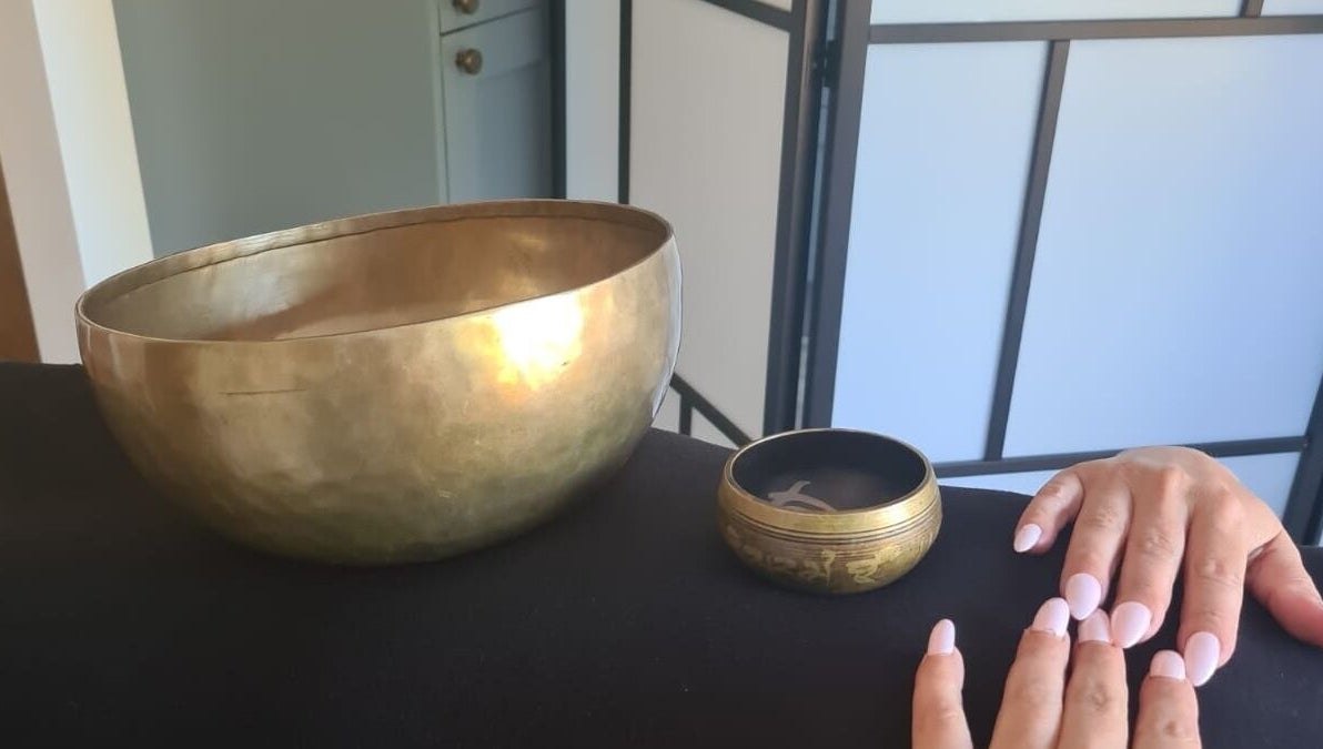 Close-up of a hand near Tibetan singing bowls at Hammersmith W6 8HS for relaxation in London, England, GB.