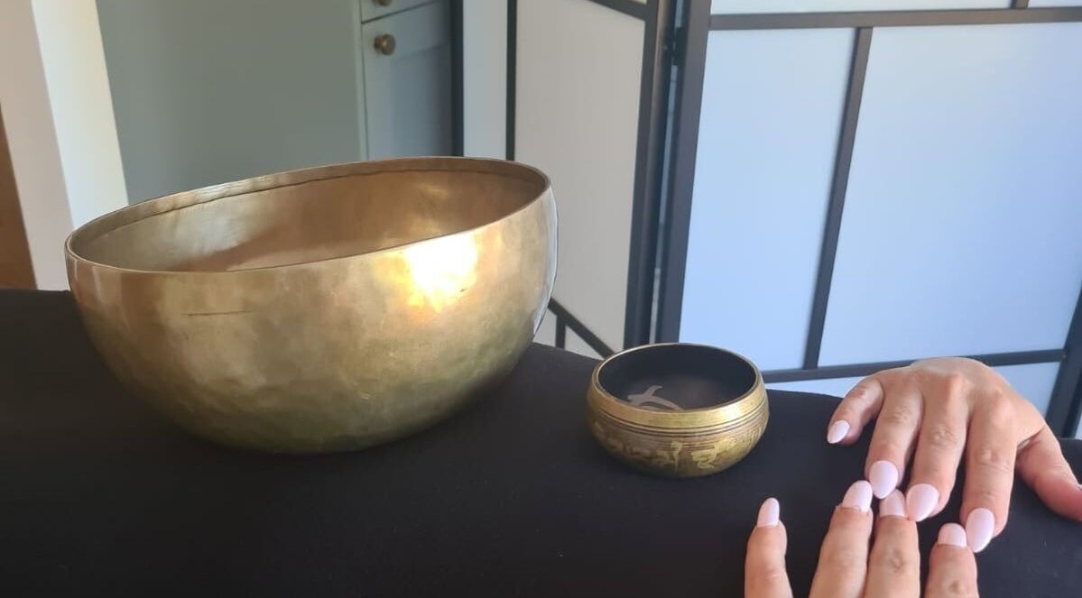 Close-up of a hand near Tibetan singing bowls at Hammersmith W6 8HS for relaxation in London, England, GB.