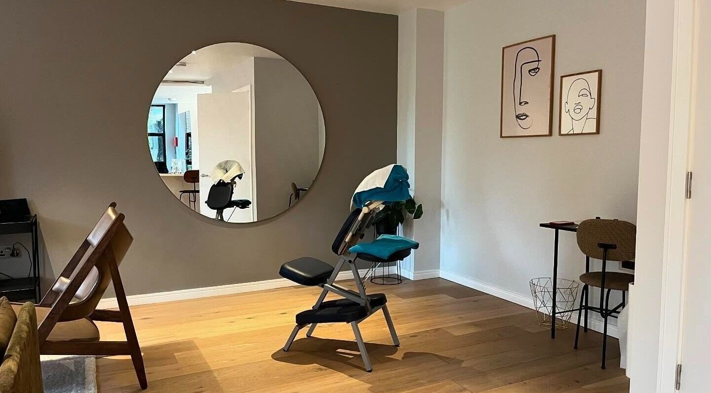 Tranquil therapy room at Elysian Therapies in South Ockendon, GB, featuring massage chair and abstract art.