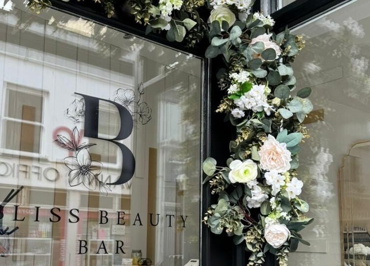 Front of Bliss Beauty Bar in Ramsey with elegant floral decor around the entrance.