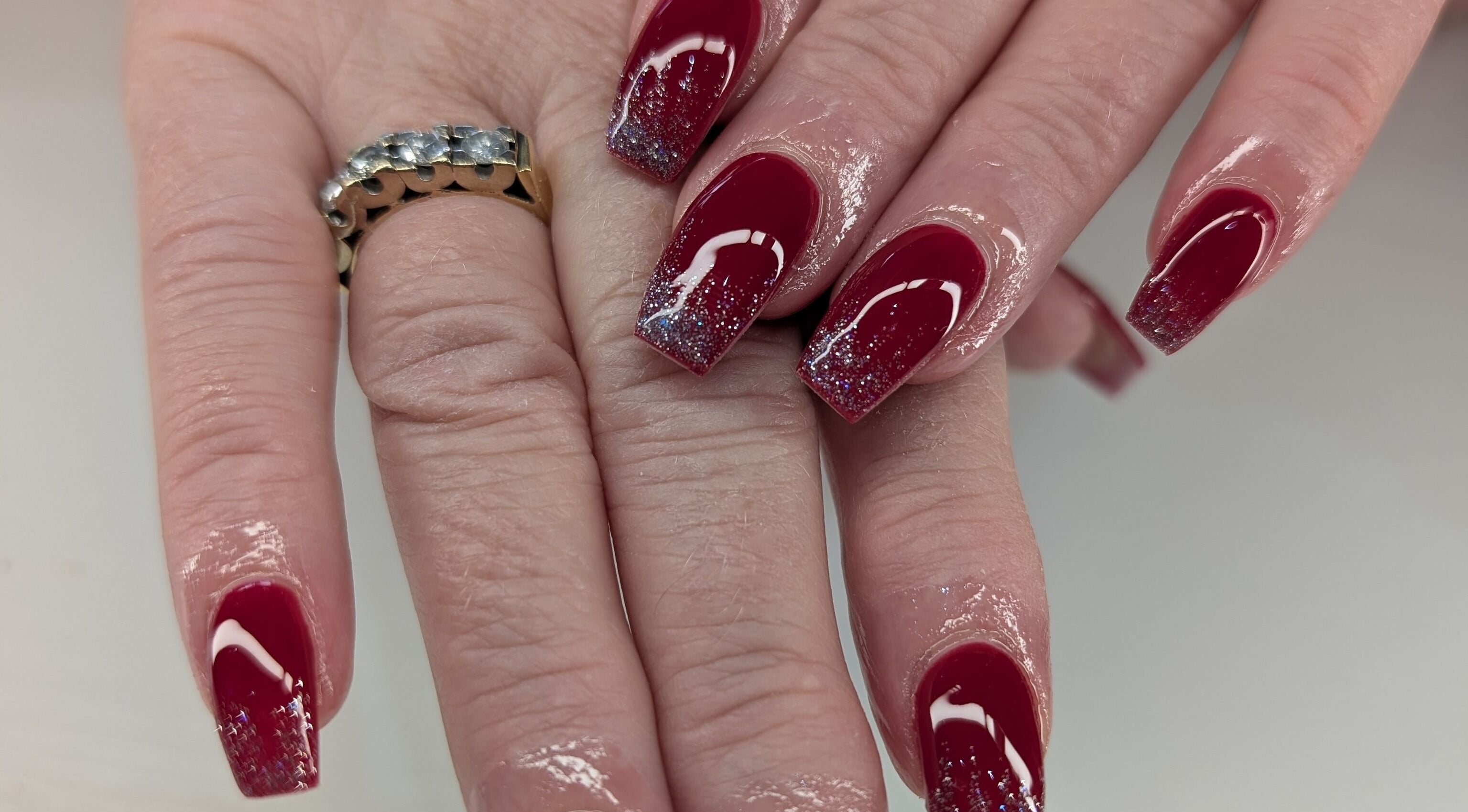 Shiny burgundy nails with glitter tips, styled at Beyond Beauty in Blyth, England, GB.