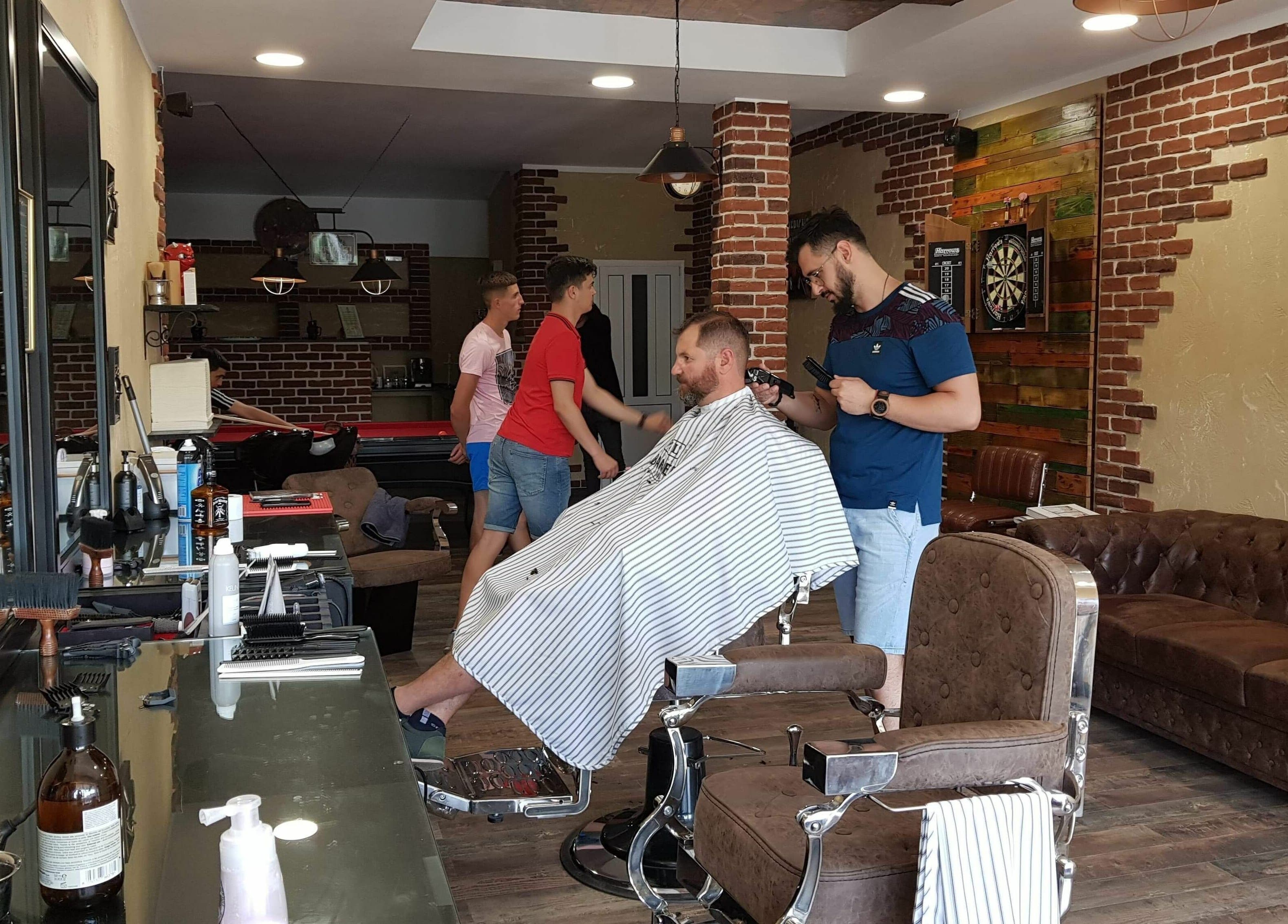 Interiorul Filaret's Barbershop, Gura Humorului, România, RO, cu clienți și stiliști ocupați.