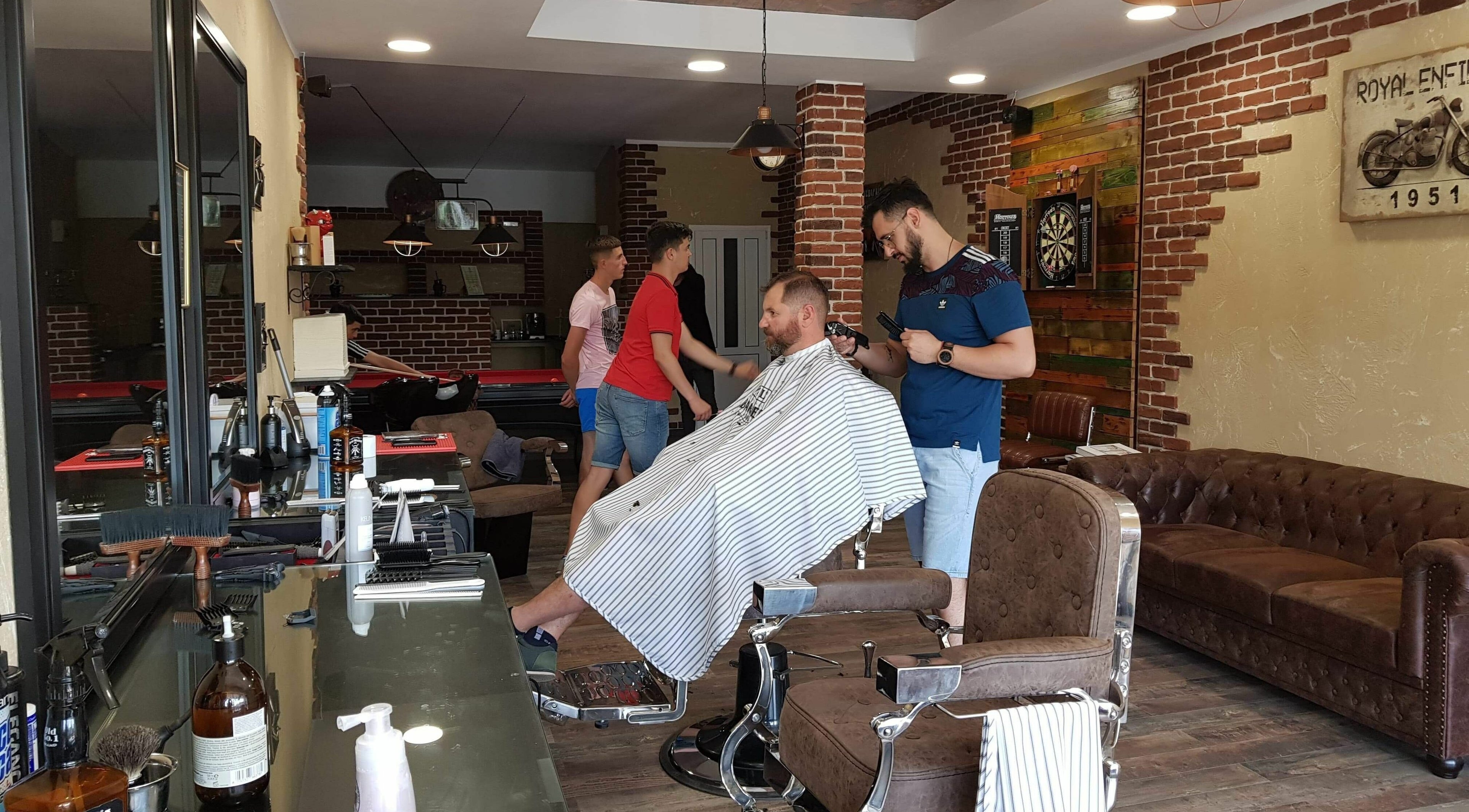 Interiorul Filaret's Barbershop, Gura Humorului, România, RO, cu clienți și stiliști ocupați.