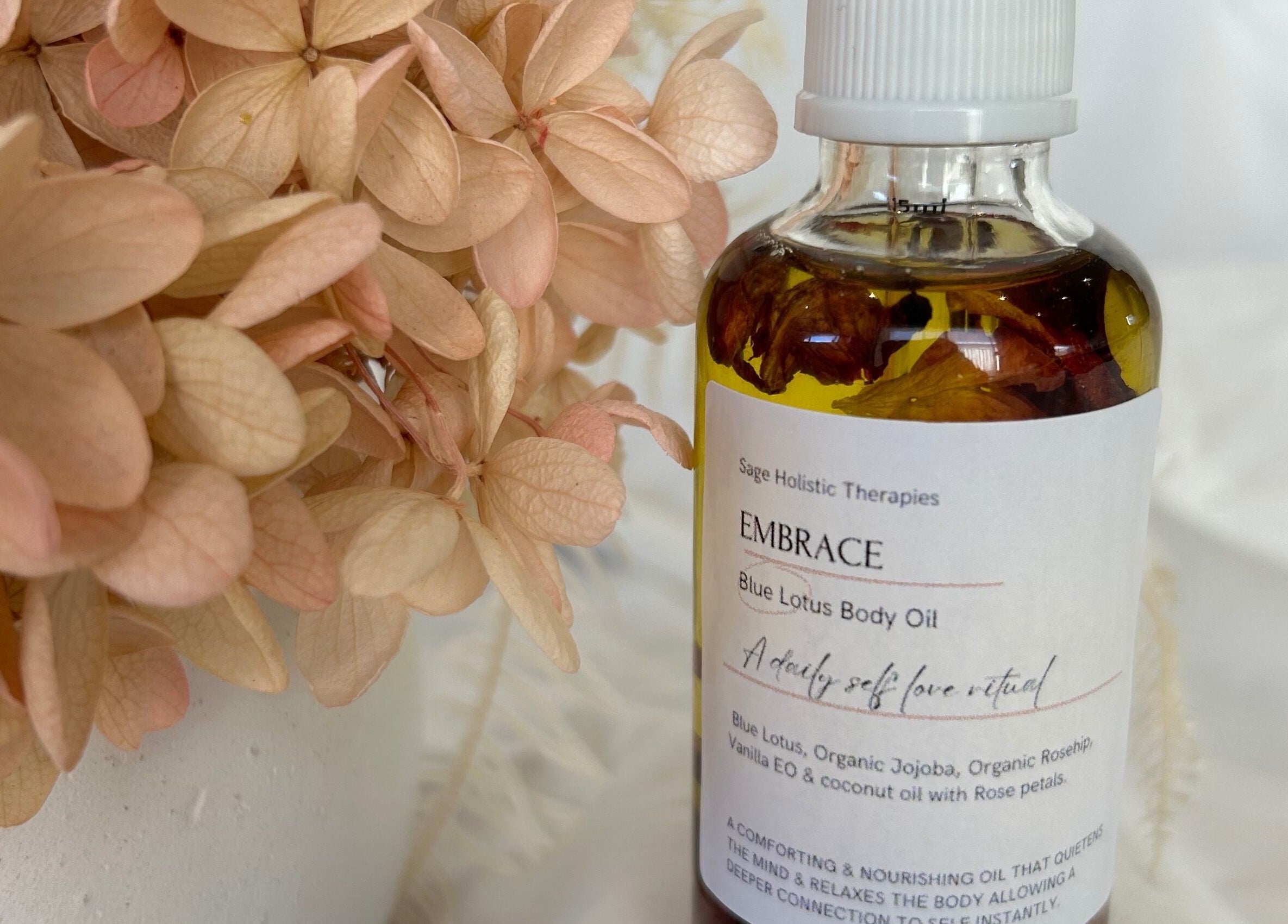 Embrace Blue Lotus Body Oil by Sage Holistic Therapies in Alkimos, Western Australia, surrounded by soft petals.