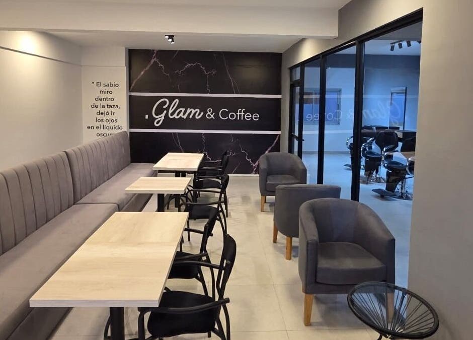 Interior del Glam & Coffee en Wilde, Provincia De Buenos Aires, AR con sofás grises y mesas de madera.