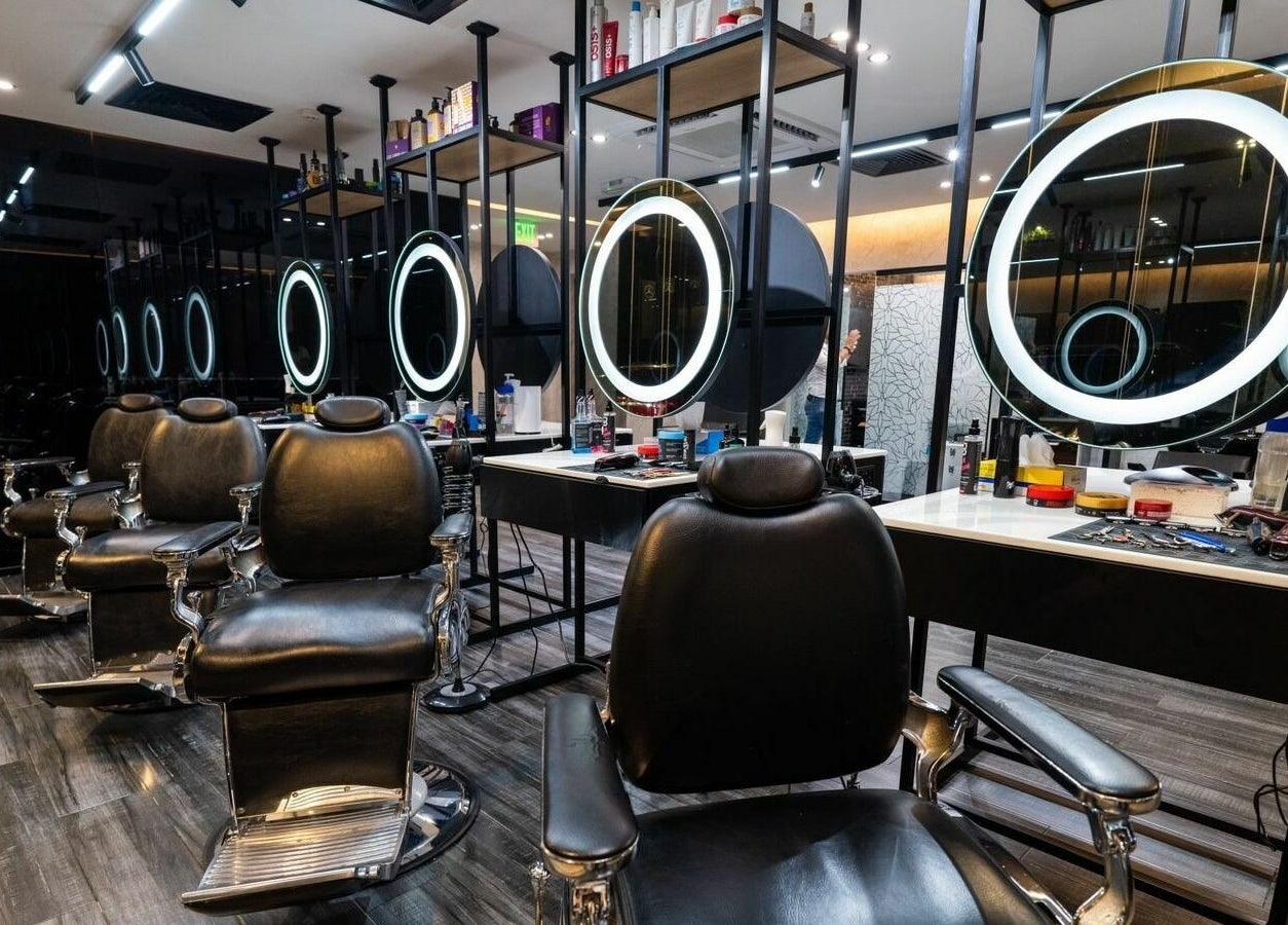 Stylish interior of Sams Barber Men Care Center in Abu Dhabi featuring modern chairs and illuminated mirrors.