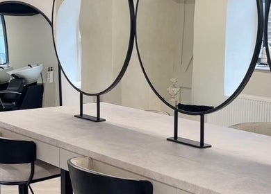 Elegant salon interior at Glam by Laura featuring round mirrors and styling chairs in Sheffield, England, GB.