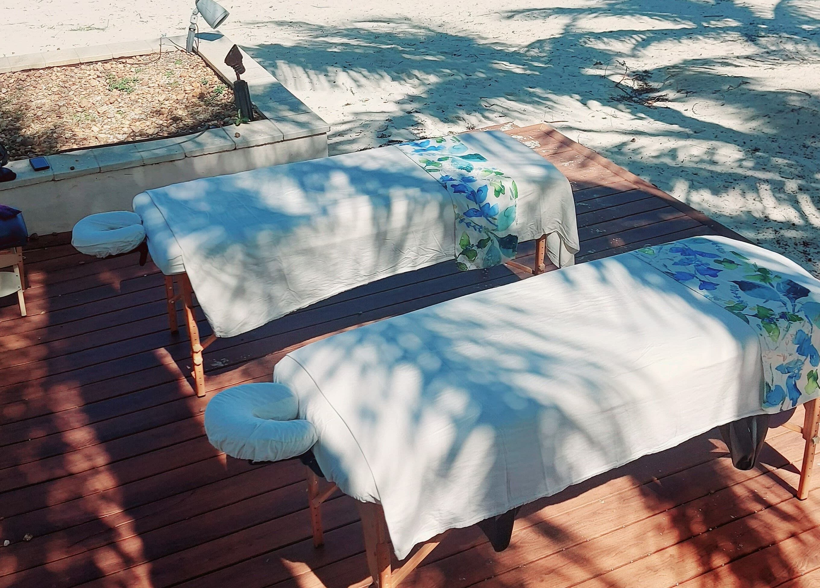 Outdoor massage tables at The Sea View Spa at February Point, Exuma, Exuma, BS, under palm shadows on a sandy beach.