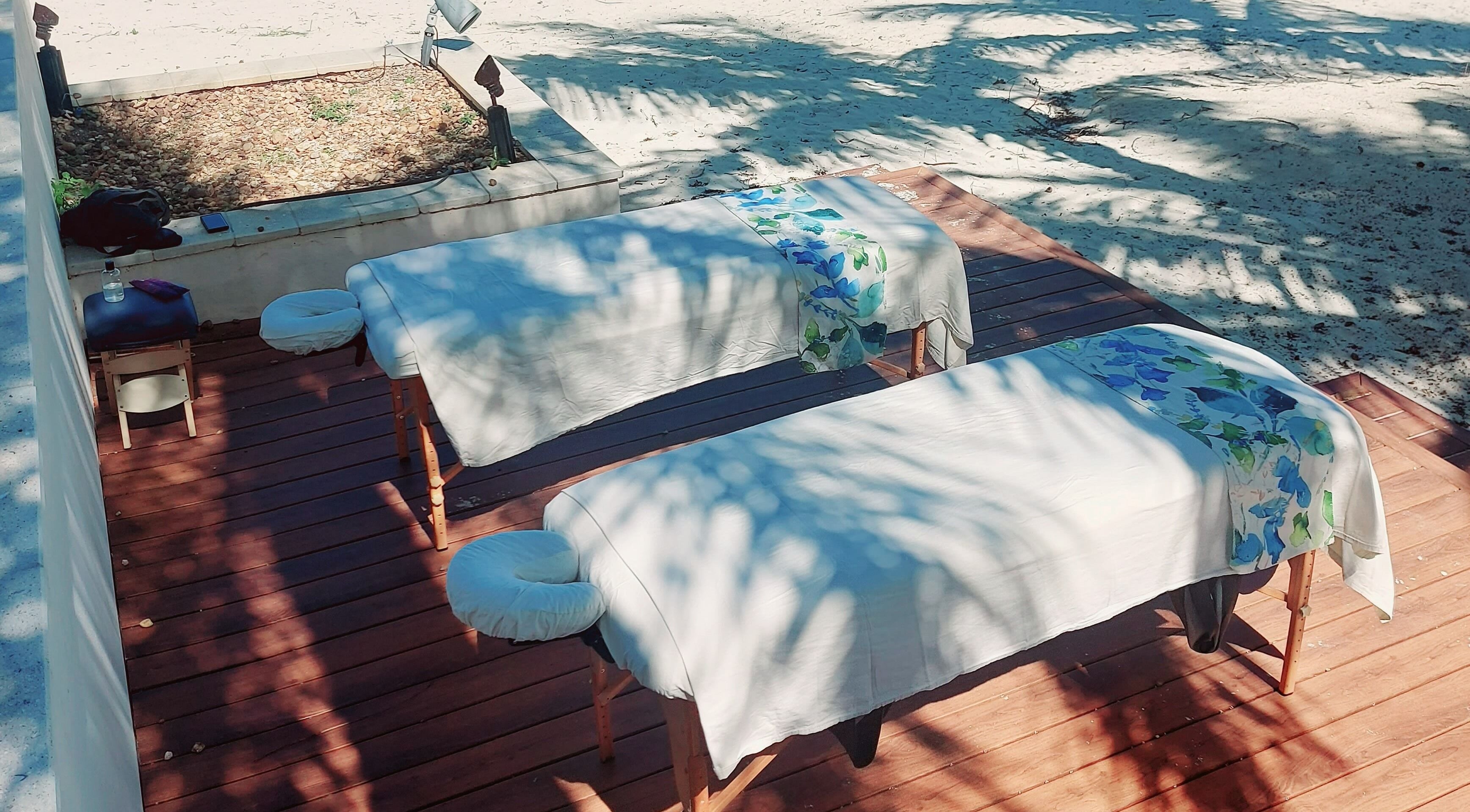 Outdoor massage tables at The Sea View Spa at February Point, Exuma, Exuma, BS, under palm shadows on a sandy beach.
