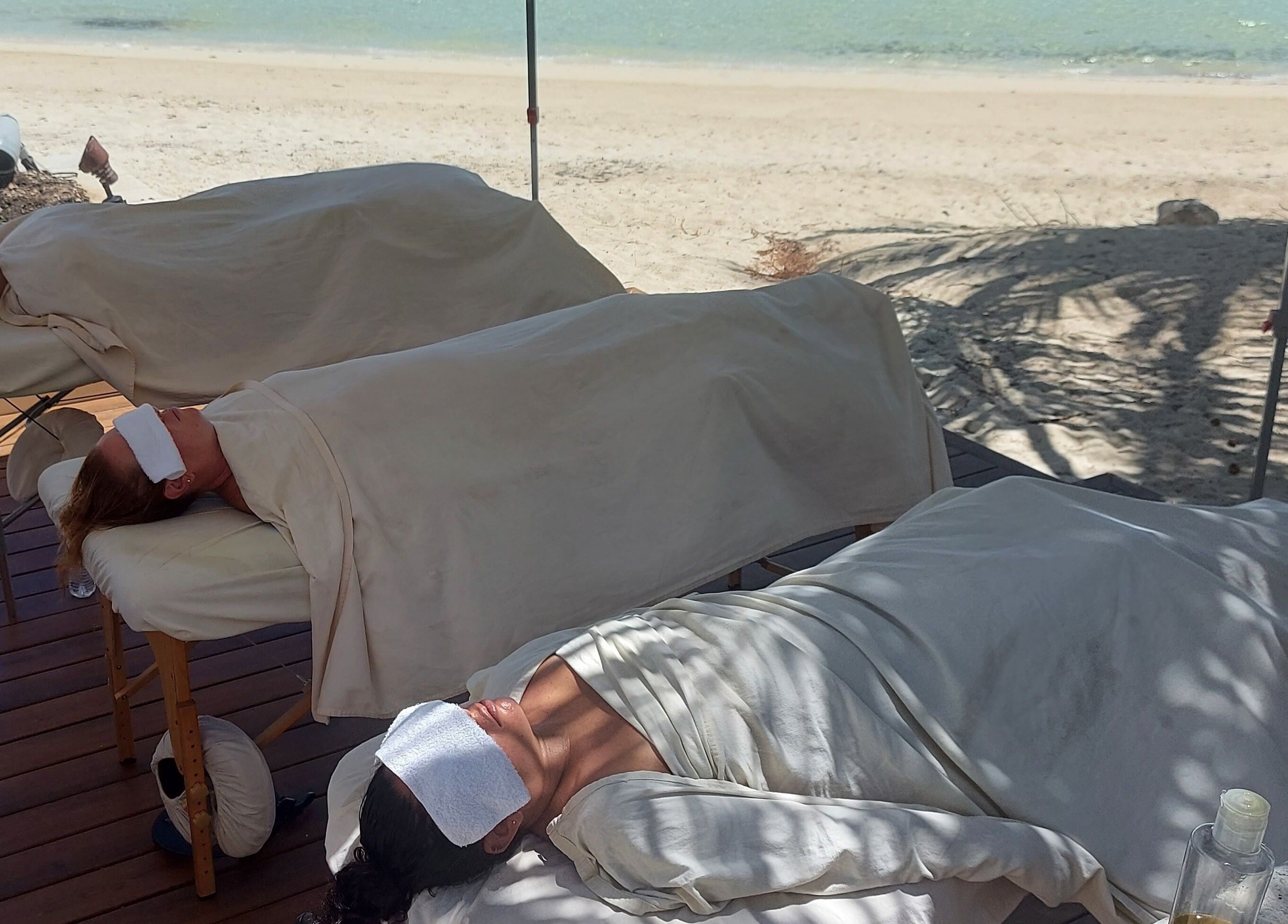 Relaxing massages on beach at The Sea View Spa at February Point, Exuma, Exuma, BS under the shade of palms.