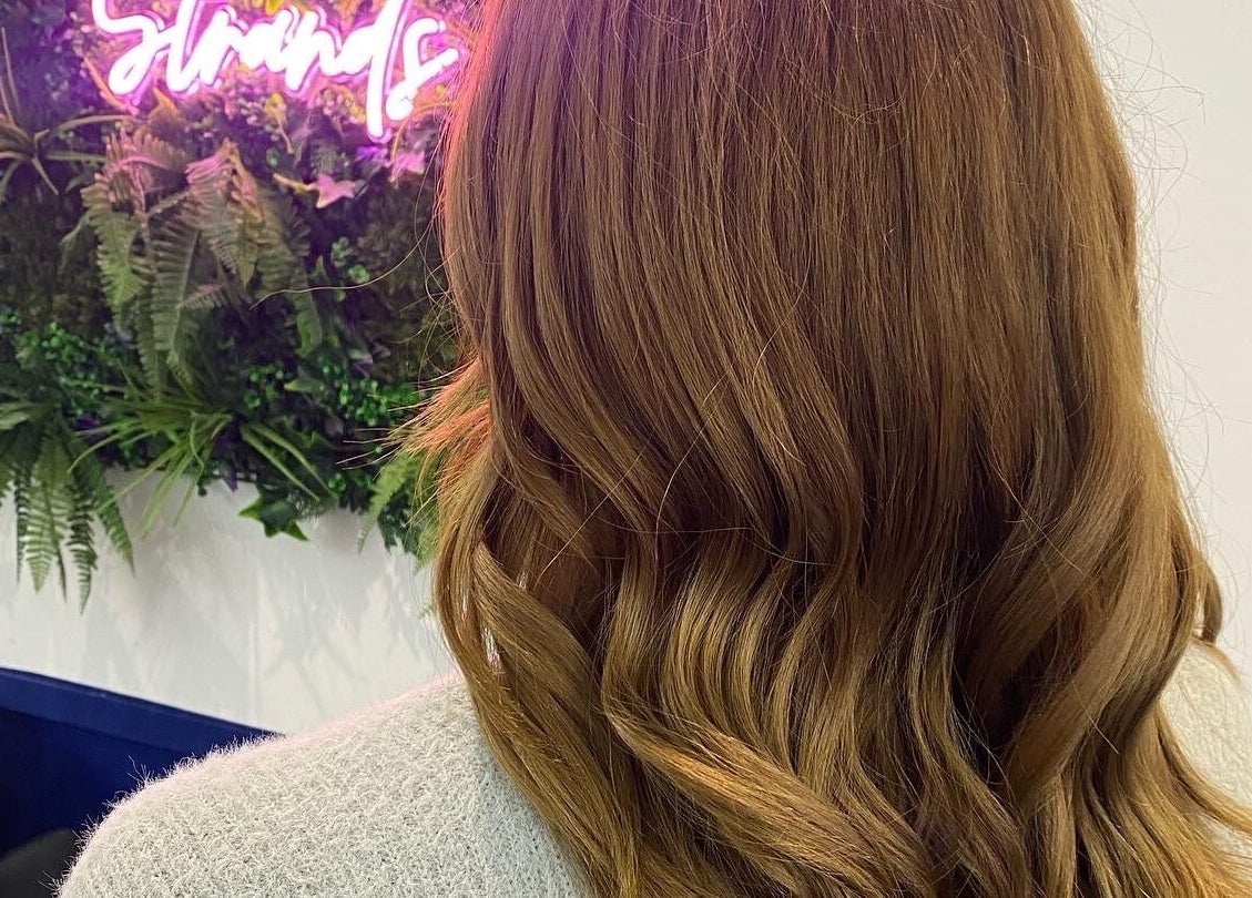 Beautiful wavy hairstyle at JR Hair Studio in Walnut Tree, England, GB with green foliage background.