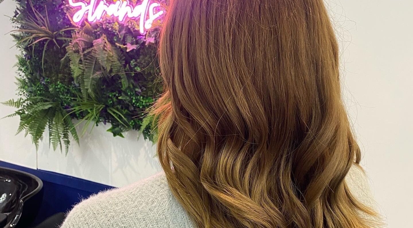 Beautiful wavy hairstyle at JR Hair Studio in Walnut Tree, England, GB with green foliage background.