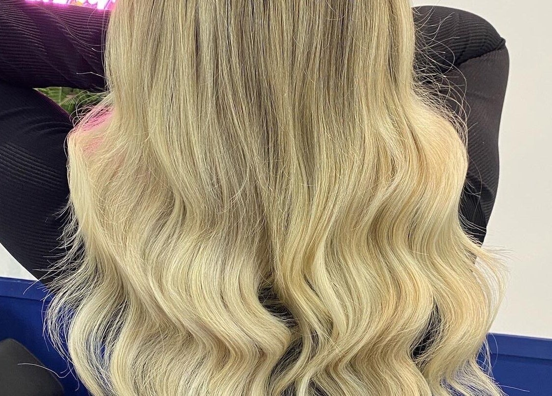 Long blonde wavy hair styled at JR Hair Studio, Walnut Tree, England, GB. Professional salon service display.