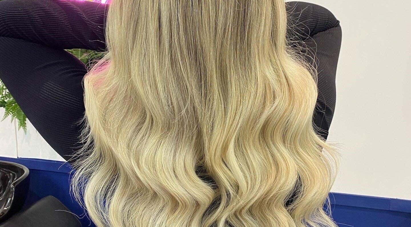 Long blonde wavy hair styled at JR Hair Studio, Walnut Tree, England, GB. Professional salon service display.