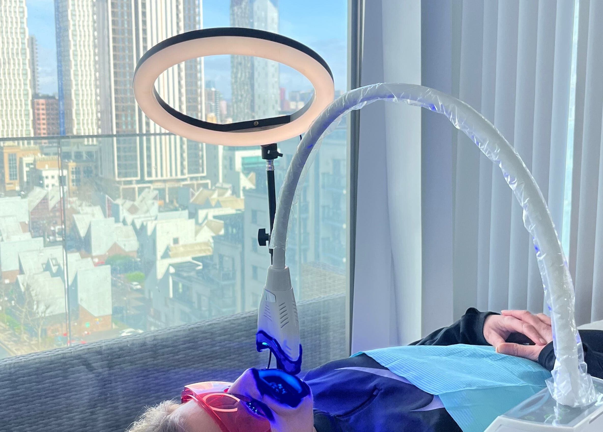 Client undergoing light therapy at City Brows London with city skyline view, London, England, GB.