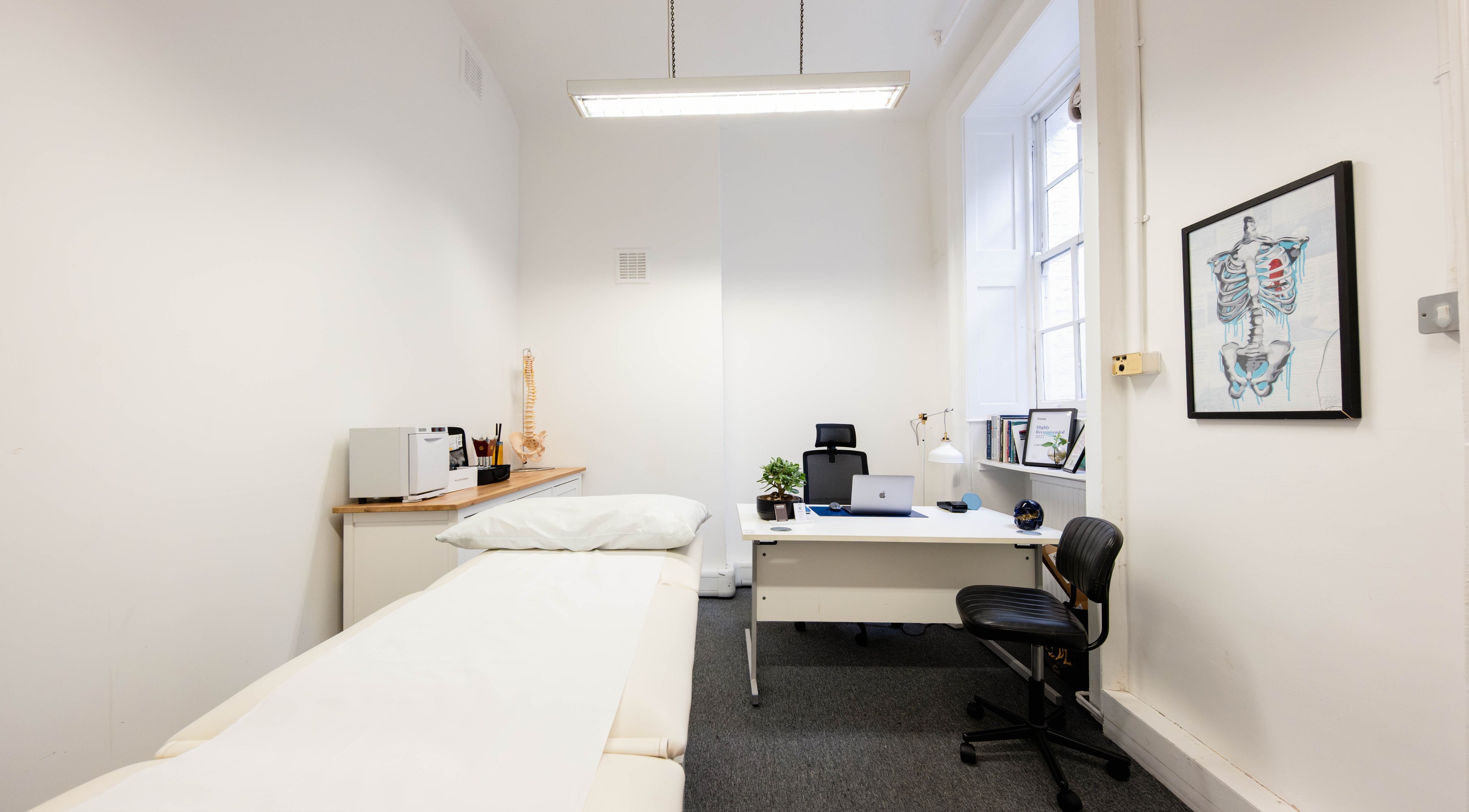 Modern treatment room at L'OSTEO Clinic in London, England, GB featuring a massage table and desk.