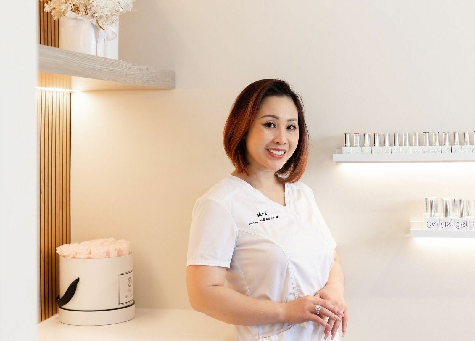 Mimi at Nails with Mimi in Earlwood, New South Wales, AU standing by nail polish display.