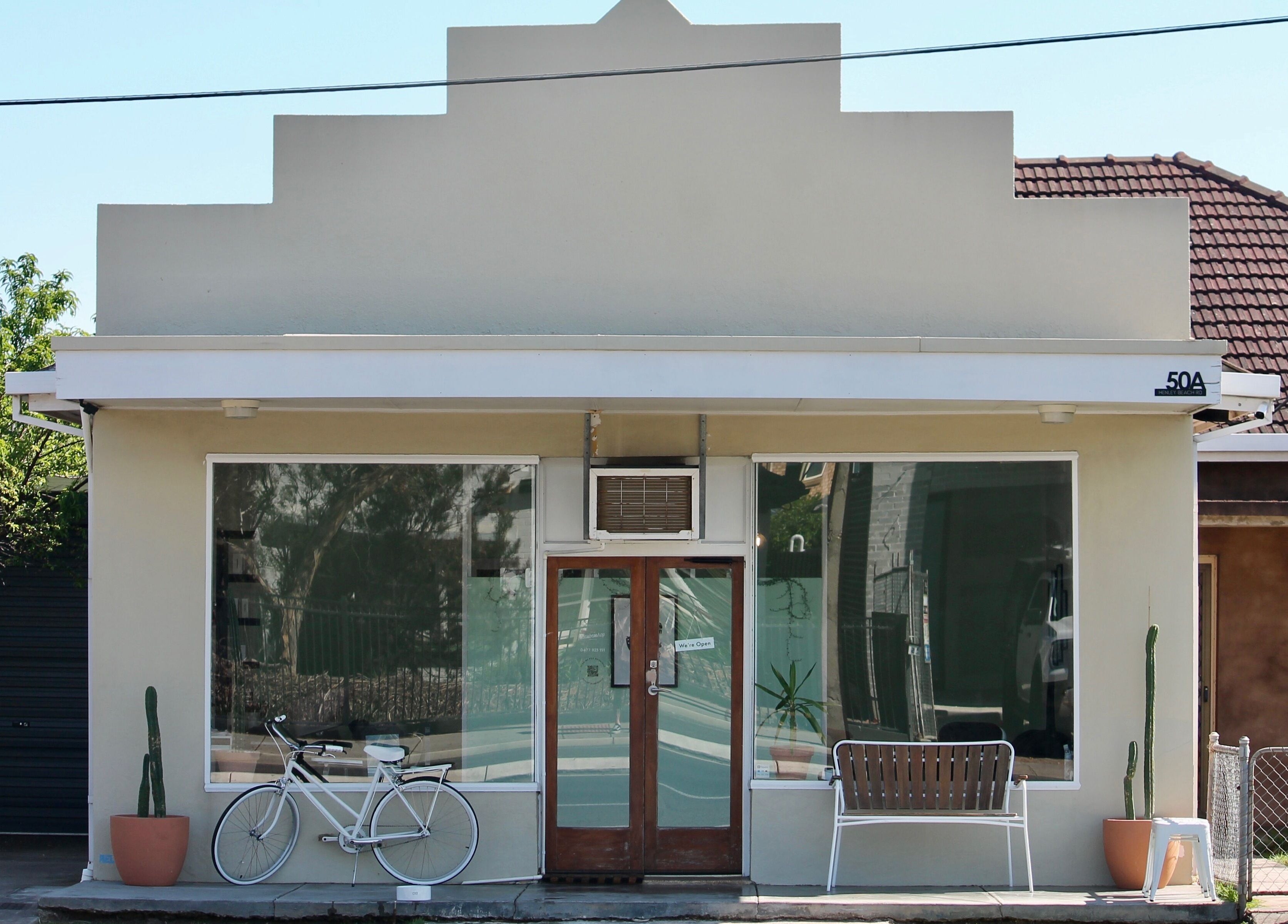 Exterior of Locale Barber Studio, West Beach, South Australia, AU, with modern facade and decorative bicycle.