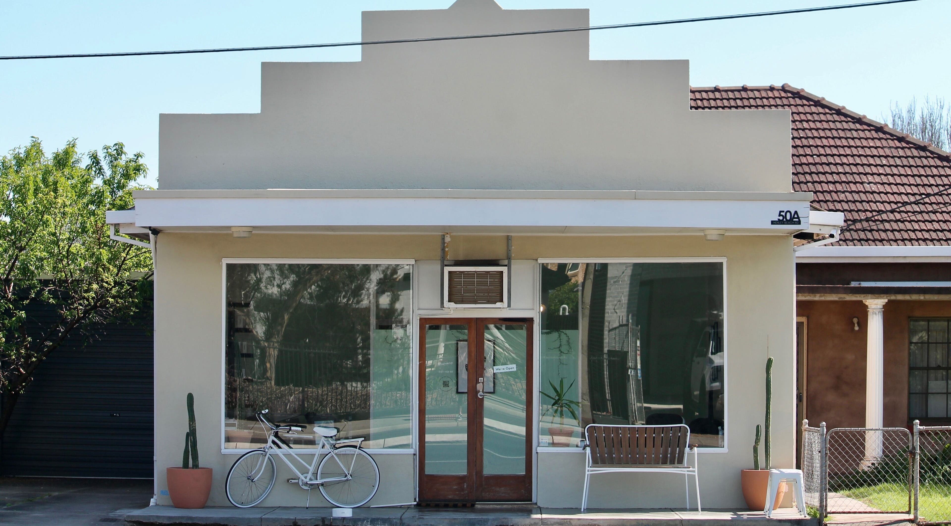 Exterior of Locale Barber Studio, West Beach, South Australia, AU, with modern facade and decorative bicycle.