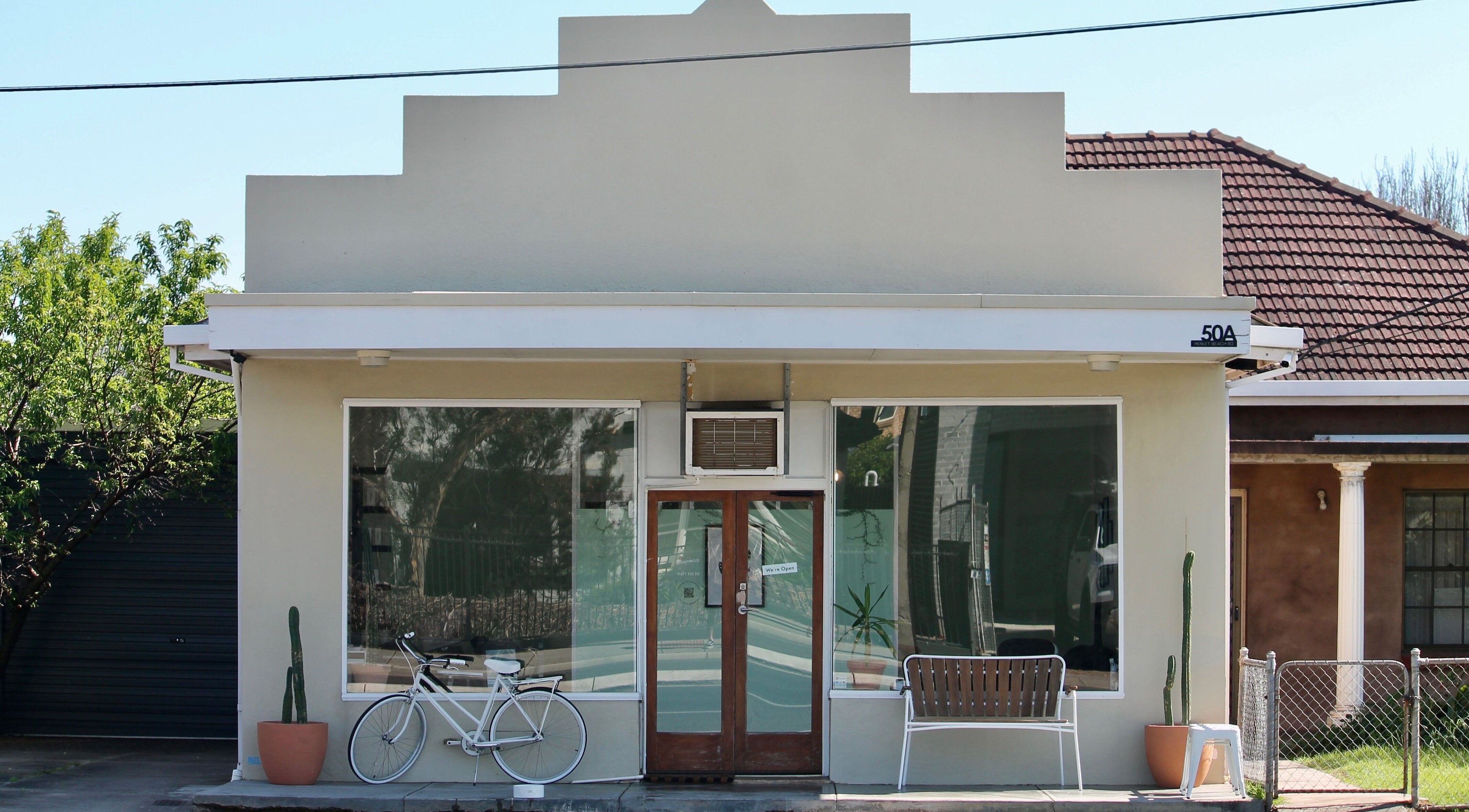 Exterior of Locale Barber Studio, West Beach, South Australia, AU, with modern facade and decorative bicycle.