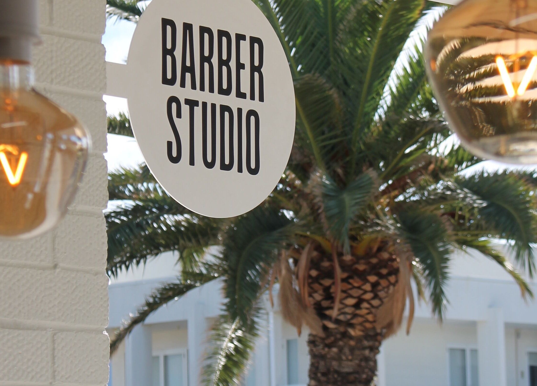 Exterior of Locale Barber Studio in West Beach, South Australia with inviting sign and warm lights.