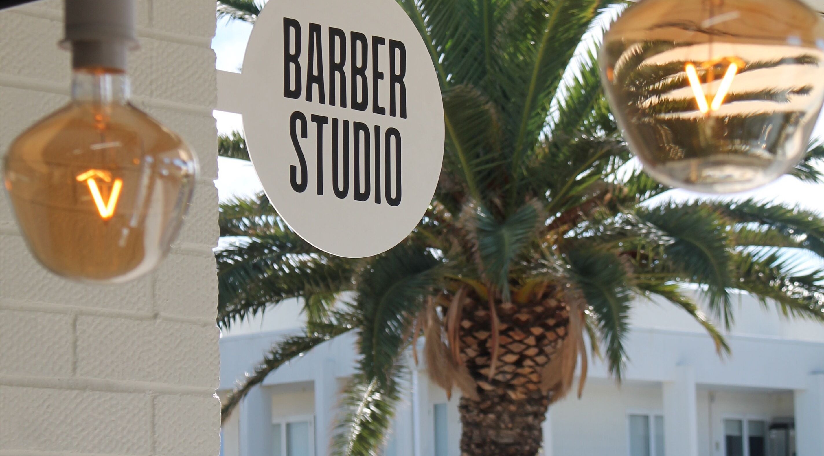 Exterior of Locale Barber Studio in West Beach, South Australia with inviting sign and warm lights.