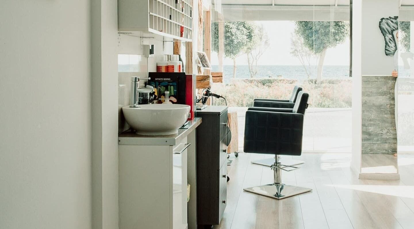 Chic interior of 7 Hair Salon, Limassol, with sea view and elegant styling chairs.