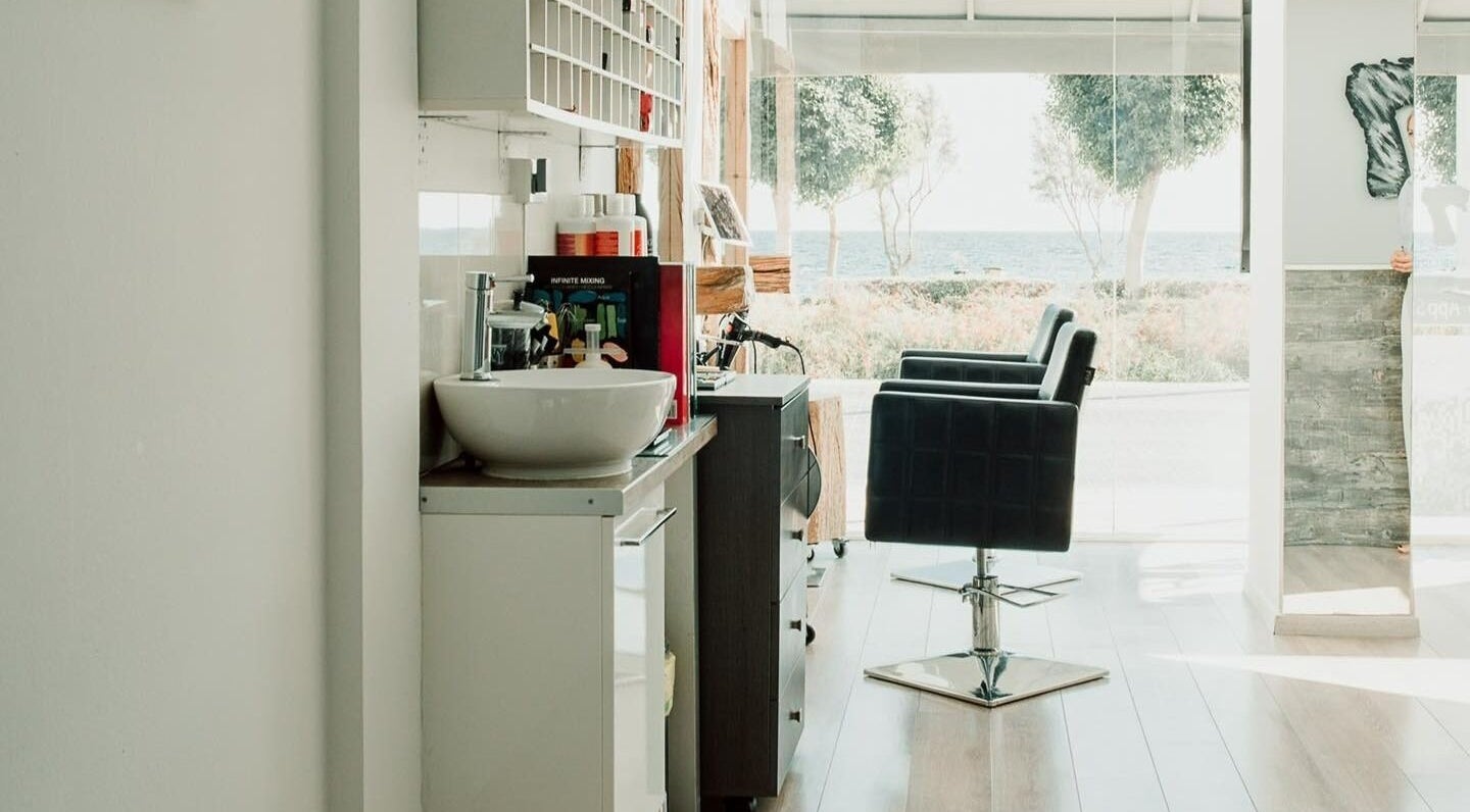 Chic interior of 7 Hair Salon, Limassol, with sea view and elegant styling chairs.