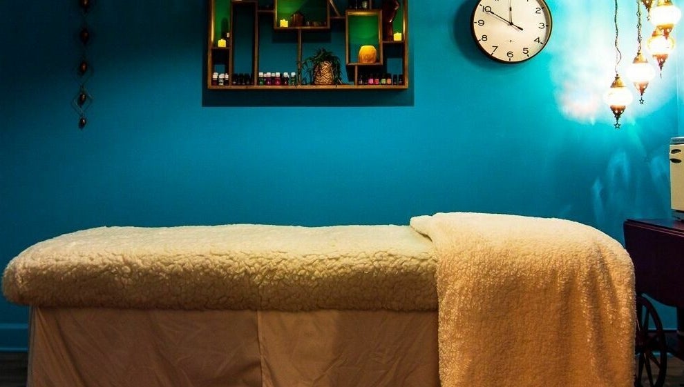 Relaxing massage room at ASHI Bodywork in Stuart, Florida, US with cozy bed and calming blue walls.