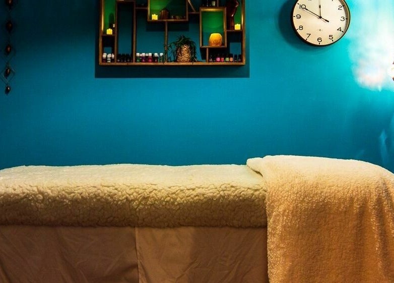 Relaxing massage room at ASHI Bodywork in Stuart, Florida, US with cozy bed and calming blue walls.