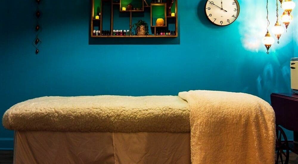 Relaxing massage room at ASHI Bodywork in Stuart, Florida, US with cozy bed and calming blue walls.