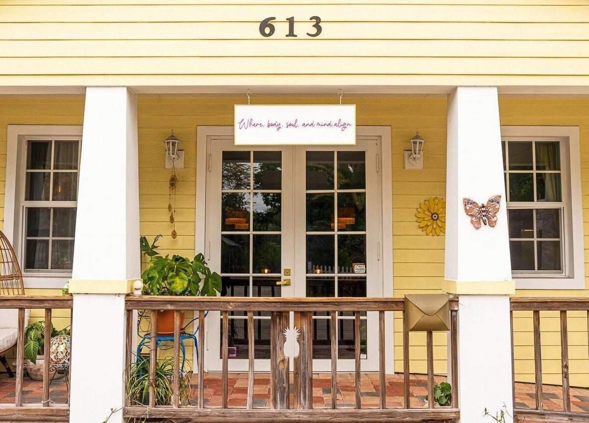 Front porch of ASHI Bodywork in Stuart, Florida, US with inviting decor and plants.