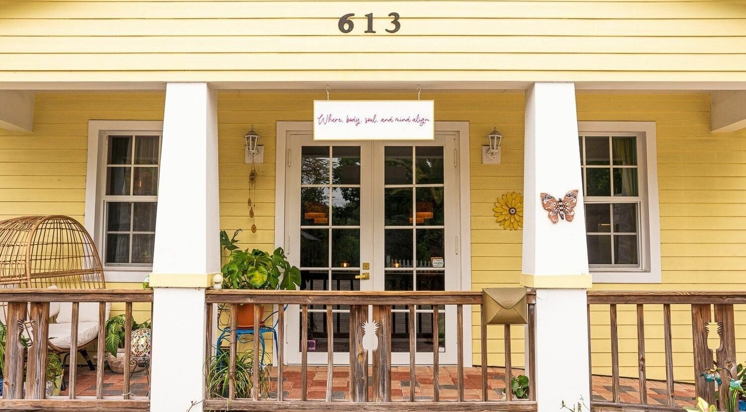 Front porch of ASHI Bodywork in Stuart, Florida, US with inviting decor and plants.
